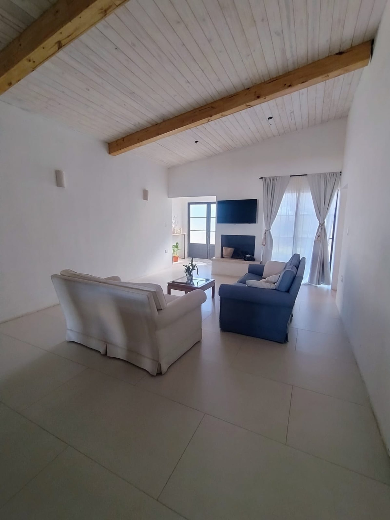 Living minimalista con techo inclinado de madera, sofás blancos y azules — proyecto Reforma Total - Ampliacion, por Atelier de Diseño Interior - Luján Macia, en Río Colorado