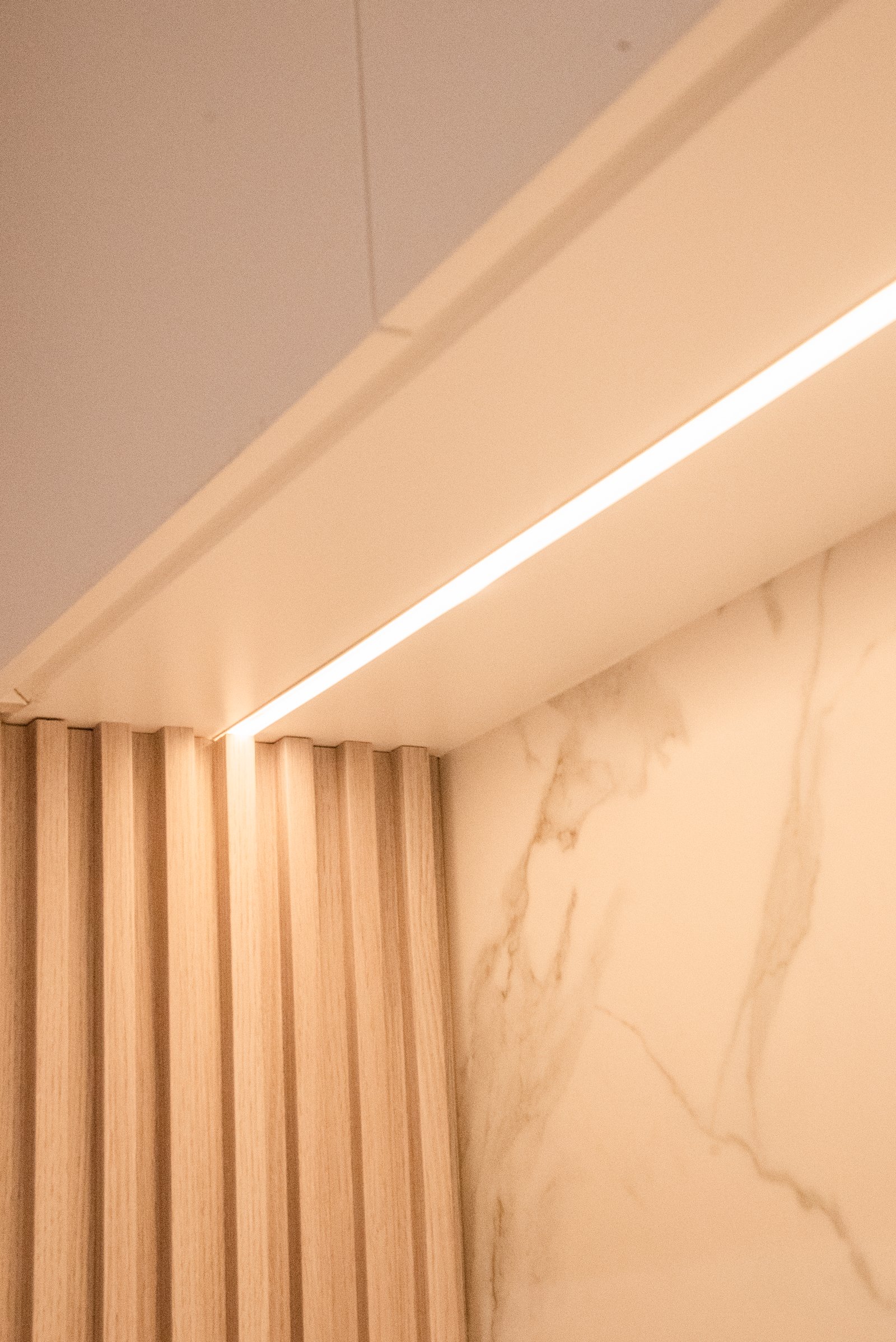 Detalle arquitectónico con revestimiento de madera y luz indirecta — proyecto QUINTANA, por ESTUDIO TEZ, en Recoleta