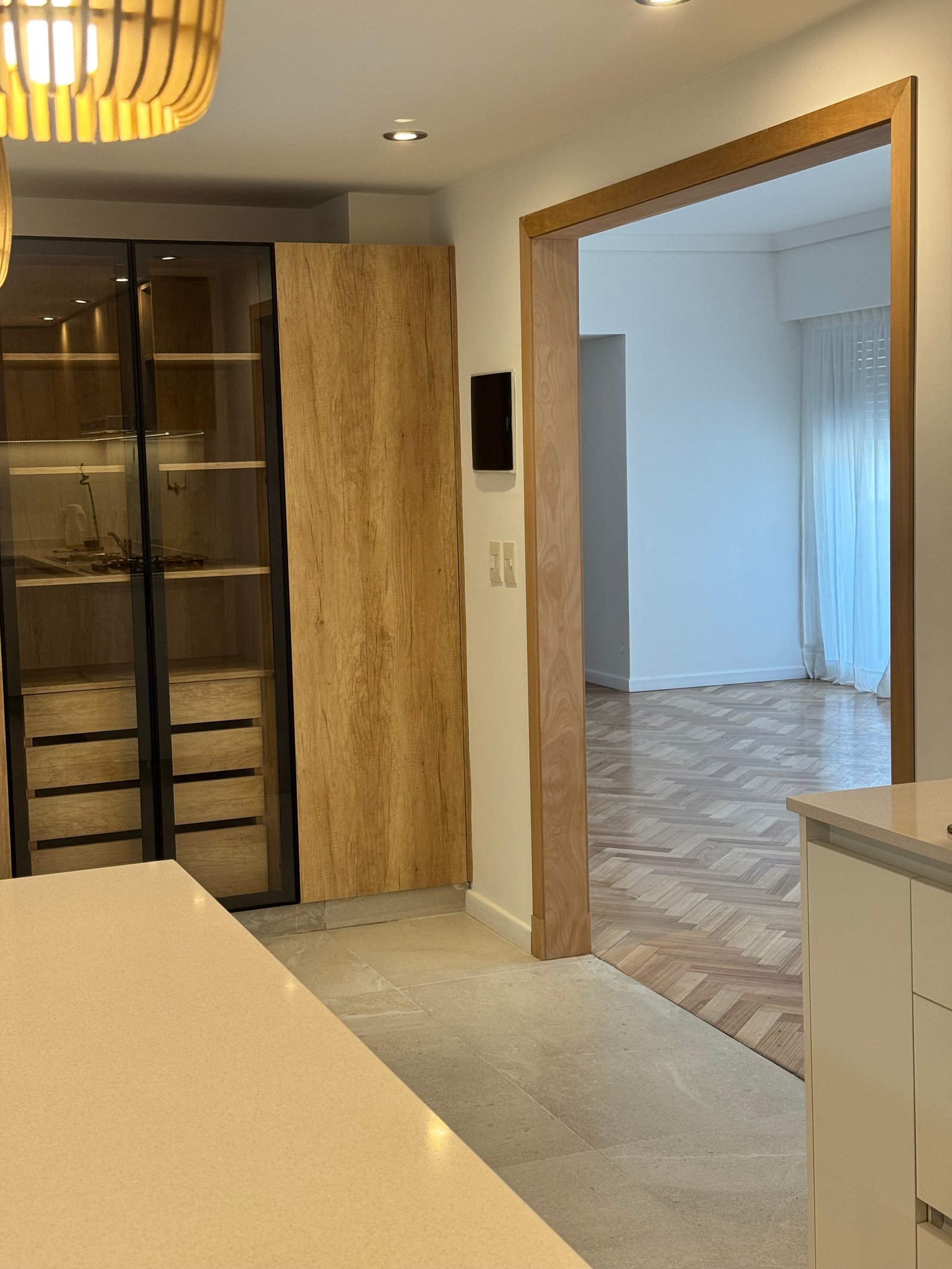 Pasillo moderno con muebles de madera y vidrio, suelo de piedra y parqué — proyecto NEWBERY, por Estudio Grupo 32, en lavalle 2501