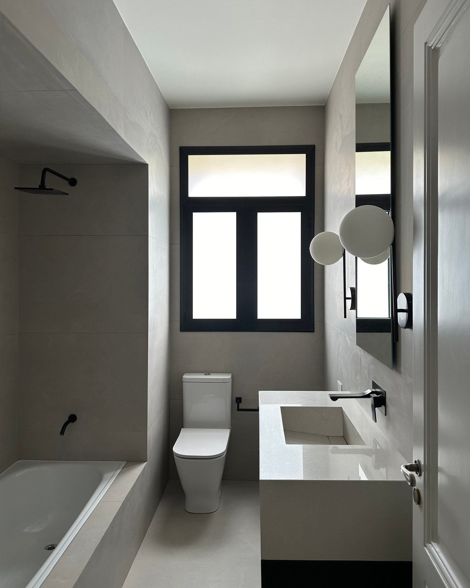 Banheiro moderno minimalista com microcimento cinza e banheira freestanding — projeto LIBERTADOR I, por ESTUDIO TEZ, em Palermo