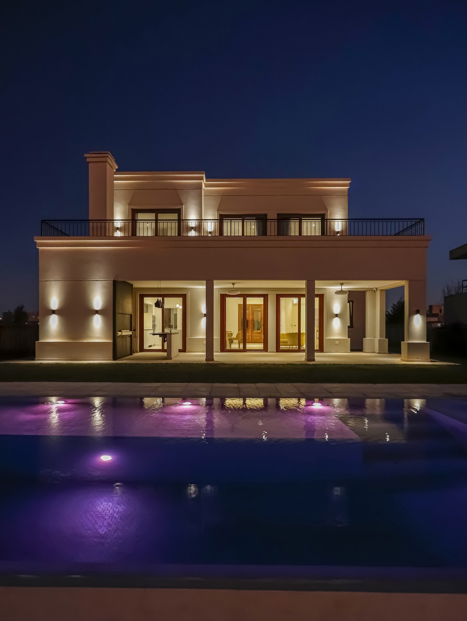 Fachada moderna con piscina iluminada de noche — proyecto Casa SS182, por EZ architects, en M3CV+6H