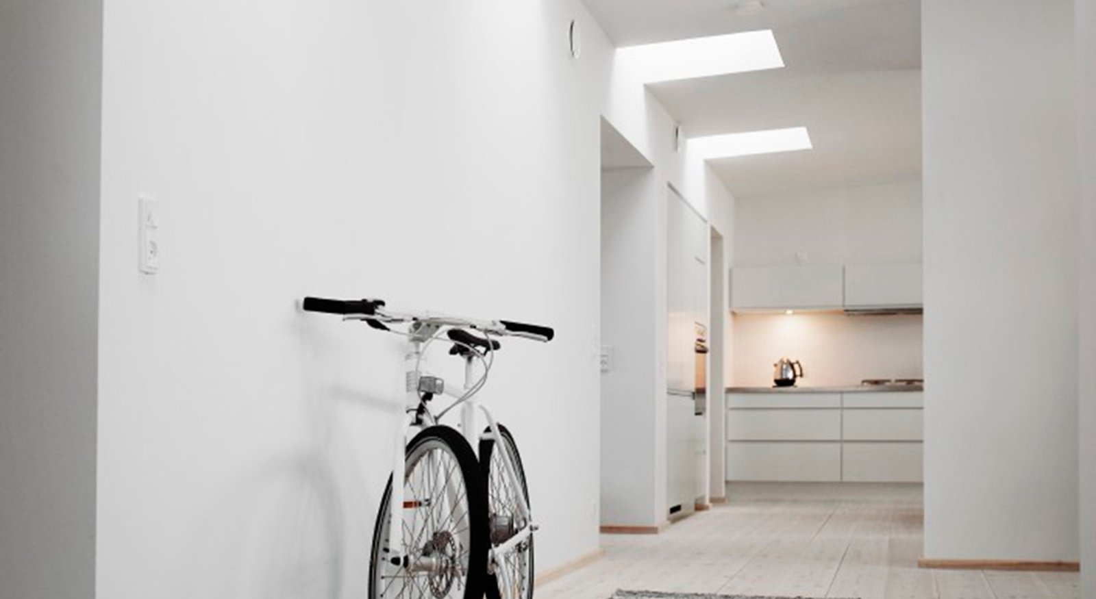 Bicicleta em corredor minimalista com claraboias — projeto Pasillo, por VELUX