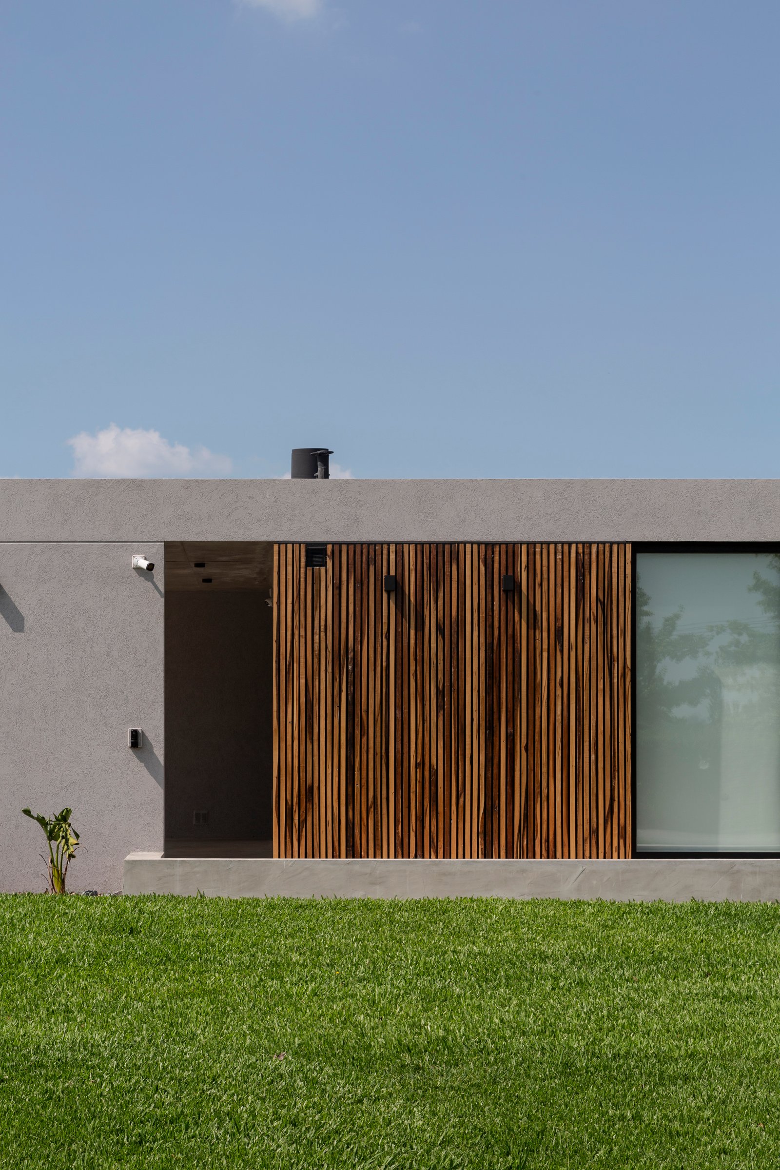 fachada moderna con revestimiento de madera y hormigón — proyecto Casa Cruz , por Grupo CRBN, en B2812 Exaltación de la Cruz