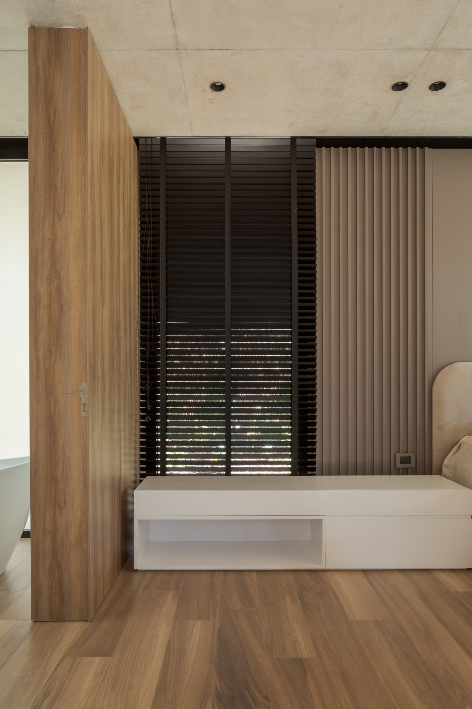 Dormitorio moderno con divisor de madera, persianas negras y almacenamiento blanco — proyecto Casa PLANALTO, por Grupo CRBN, en Av. Pres. Perón 10298