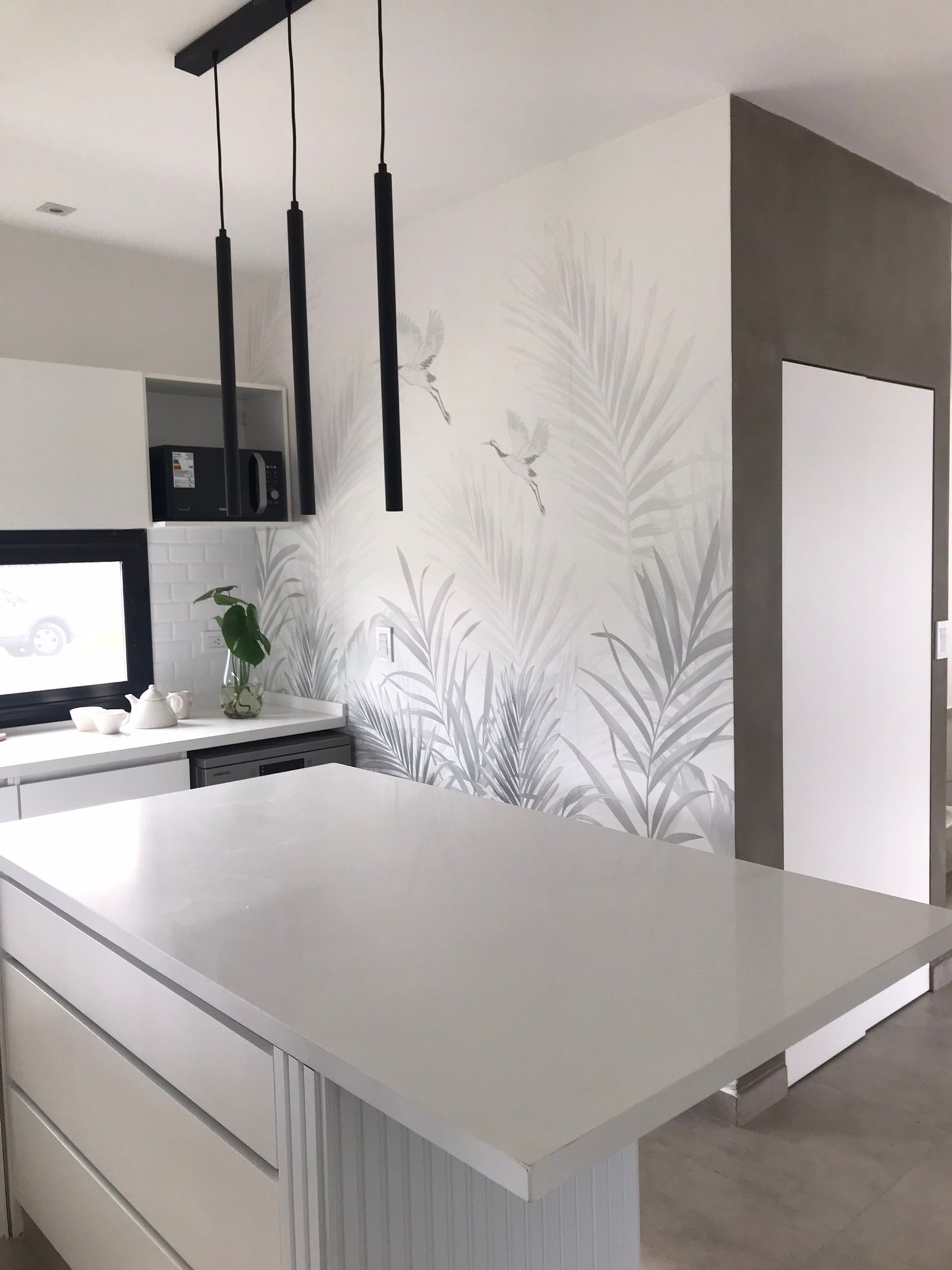 Cocina moderna con isla de piedra blanca, lámparas lineales negras y papel tapiz botánico — proyecto Mural para cocina, por Picma Empapelados, Murales, Esmerilados, Prints ,Papeles