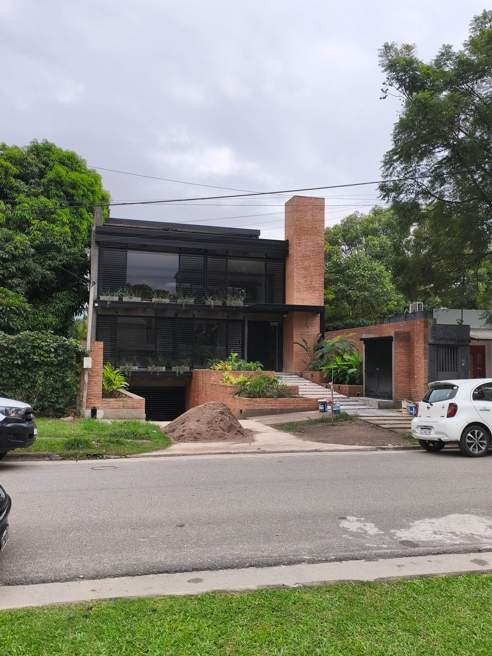 Casa moderna com fachada de tijolos e amplas janelas — projeto GARDEN OFFICE, por HMCONSTRUCCIONES, em San Lorenzo 146