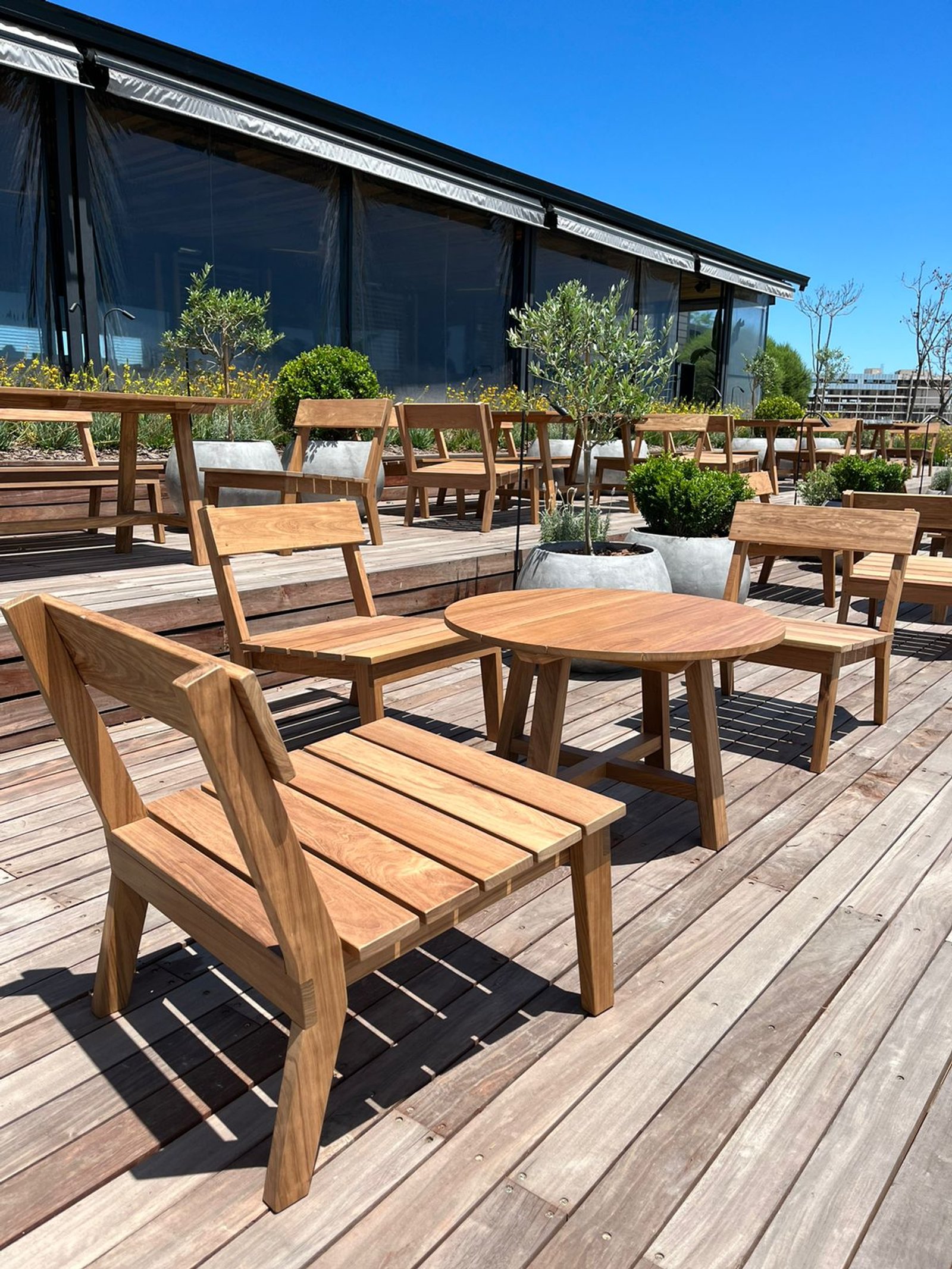 comedor exterior con mesas y sillas de madera bajo pérgola — proyecto MANSO - Restaurante, por GALPON OSUNA, en Nordelta