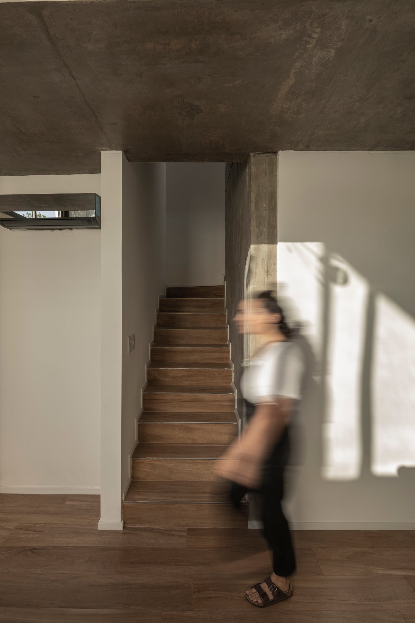 Escada flutuante moderna com concreto e luz natural — projeto Casa Emilia, por Grupo CRBN, em Parque Leloir