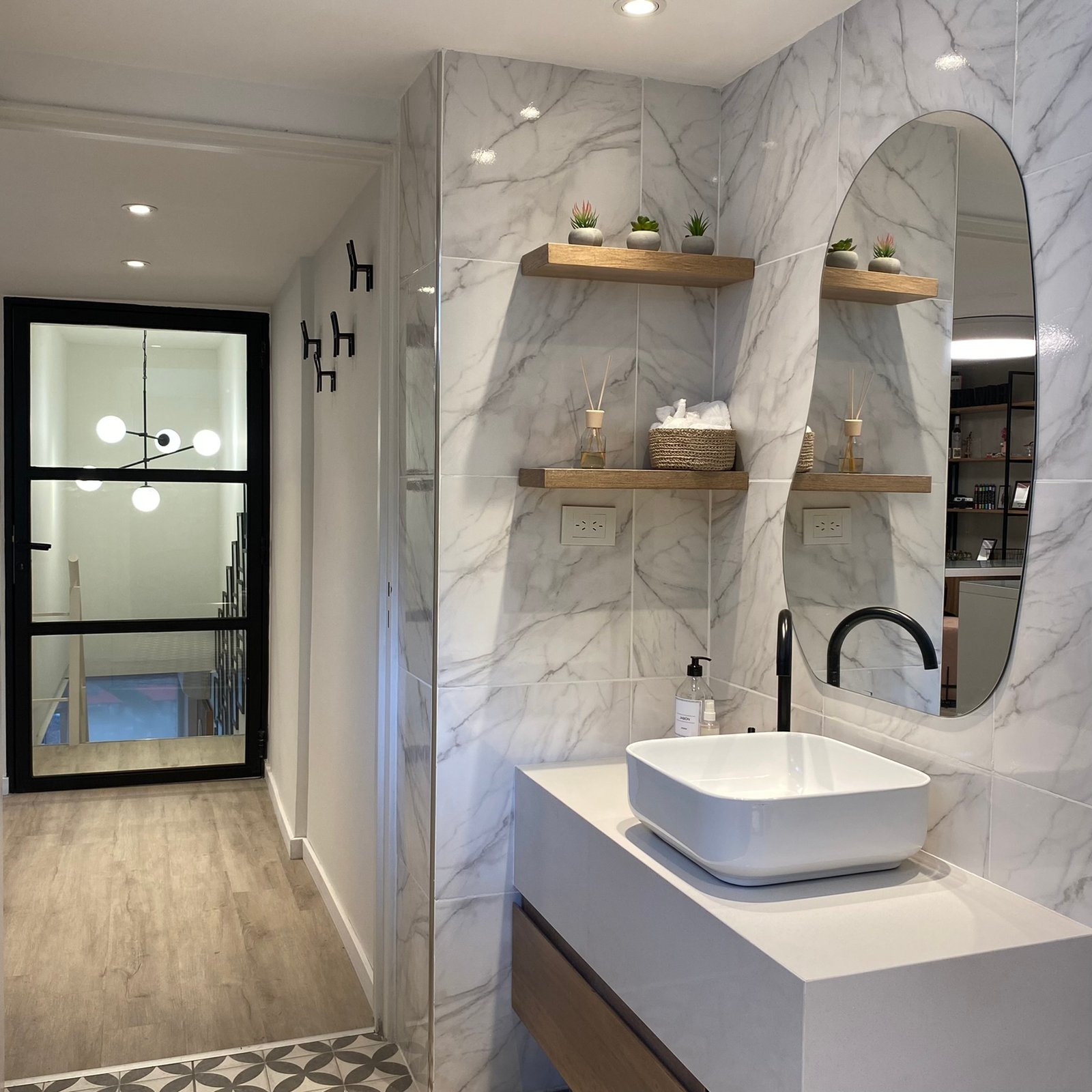 Baño moderno con detalles en mármol y grifería negra — proyecto Estudio MDBK, por MDBK Arquitectura, en Almagro