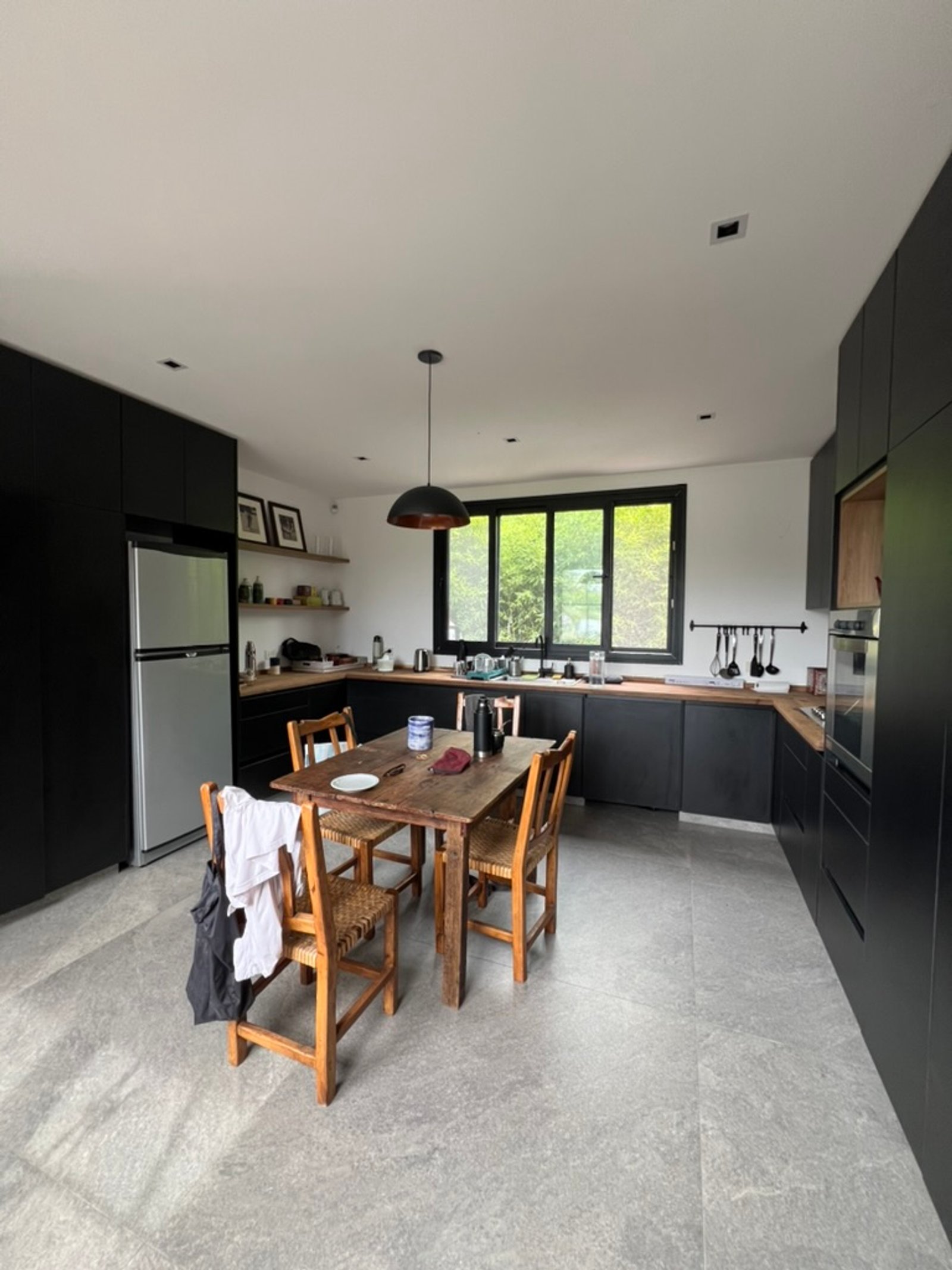 Cocina moderna de planta abierta con comedor, gabinetes negros y piso de piedra — proyecto CASA RZ, por SEDE Arq., en Pilar
