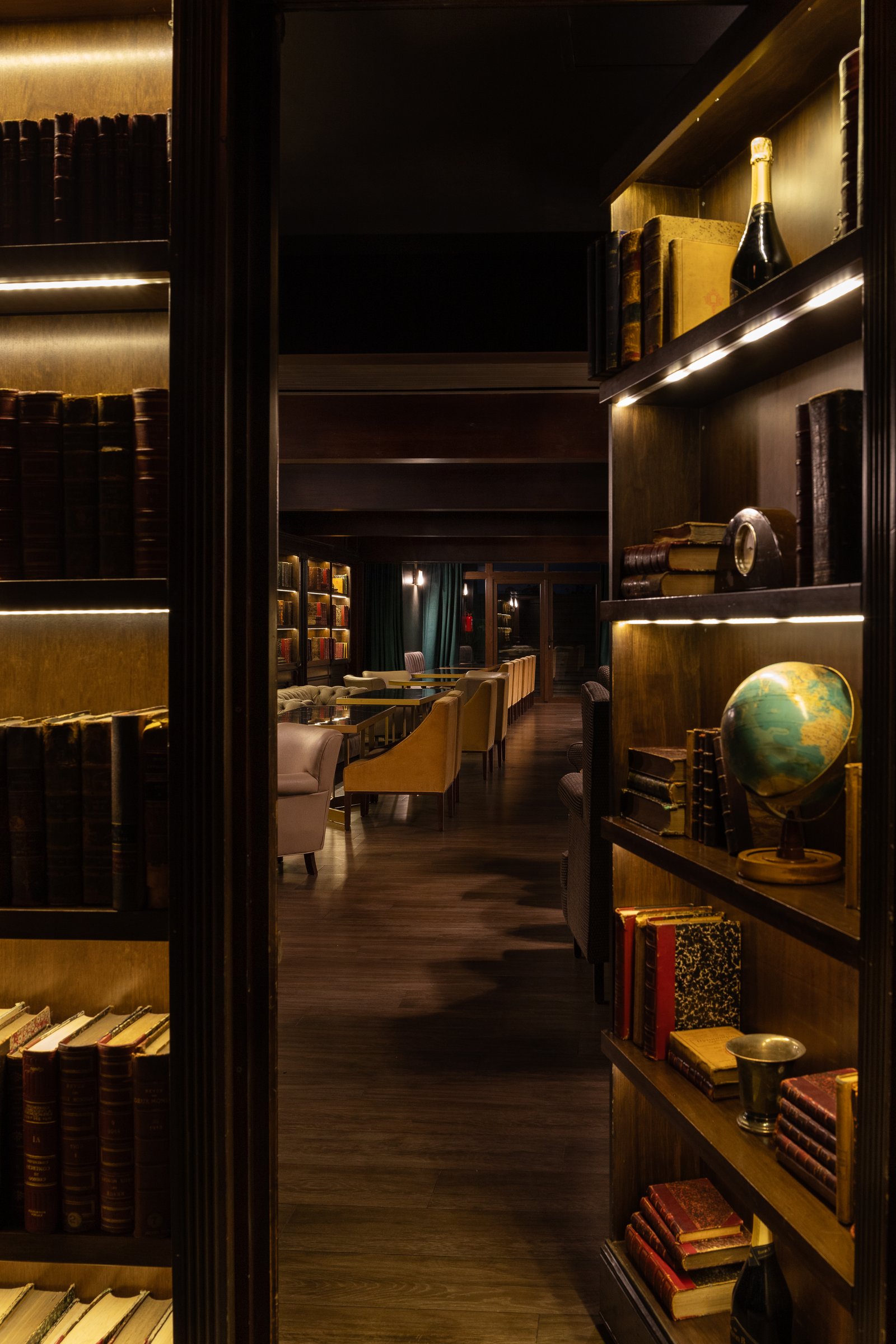 Biblioteca clássica com poltronas modernas e luz quente indireta — projeto PRESIDENTE BAR HIPODROMO, por AB ARQUITECTURA, em San Isidro