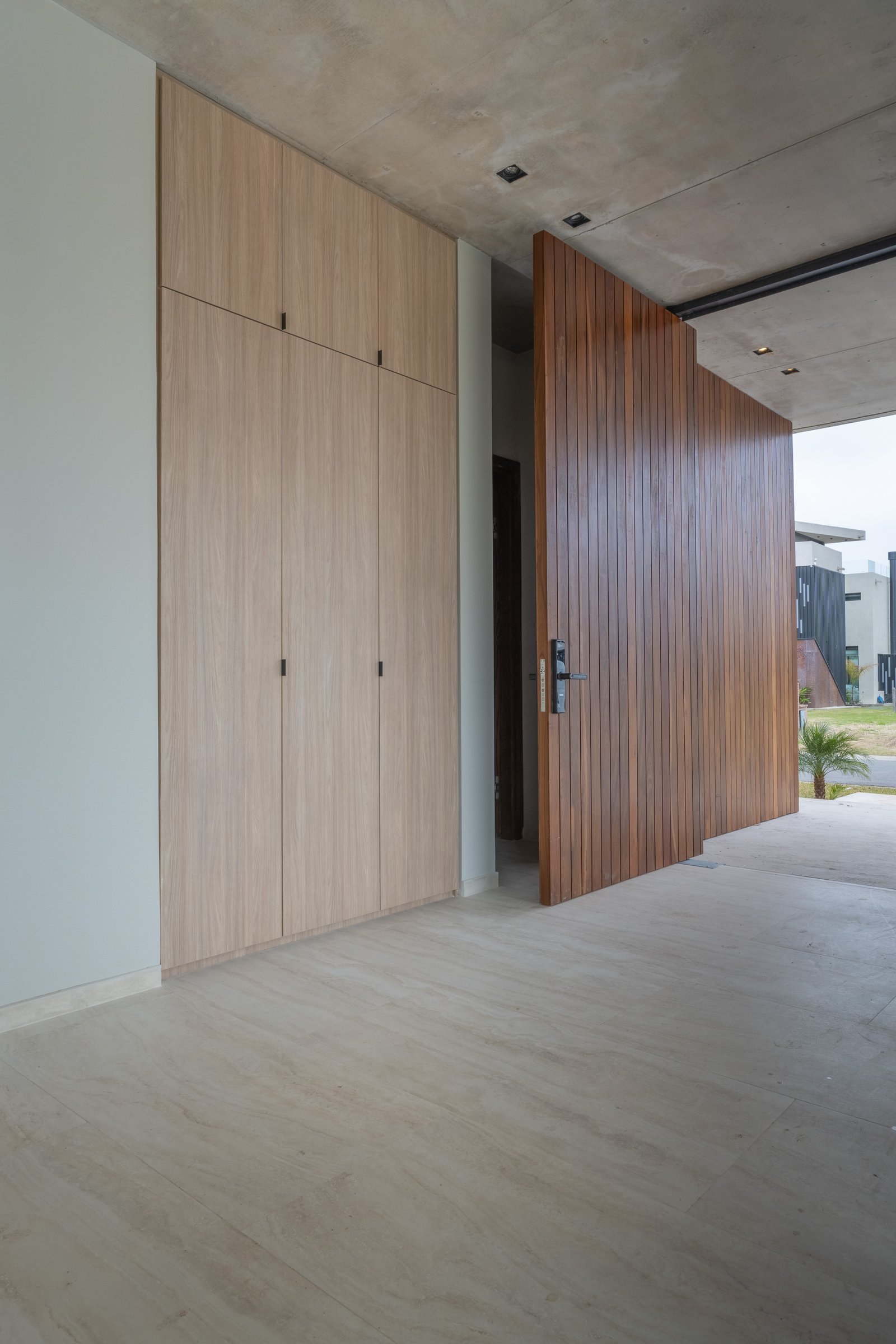corredor moderno com armário de madeira e porta pivotante gigante — projeto Yacht - Estudio CCWay, por ABEJA CONCEPT, em Av. de la Ribera 560