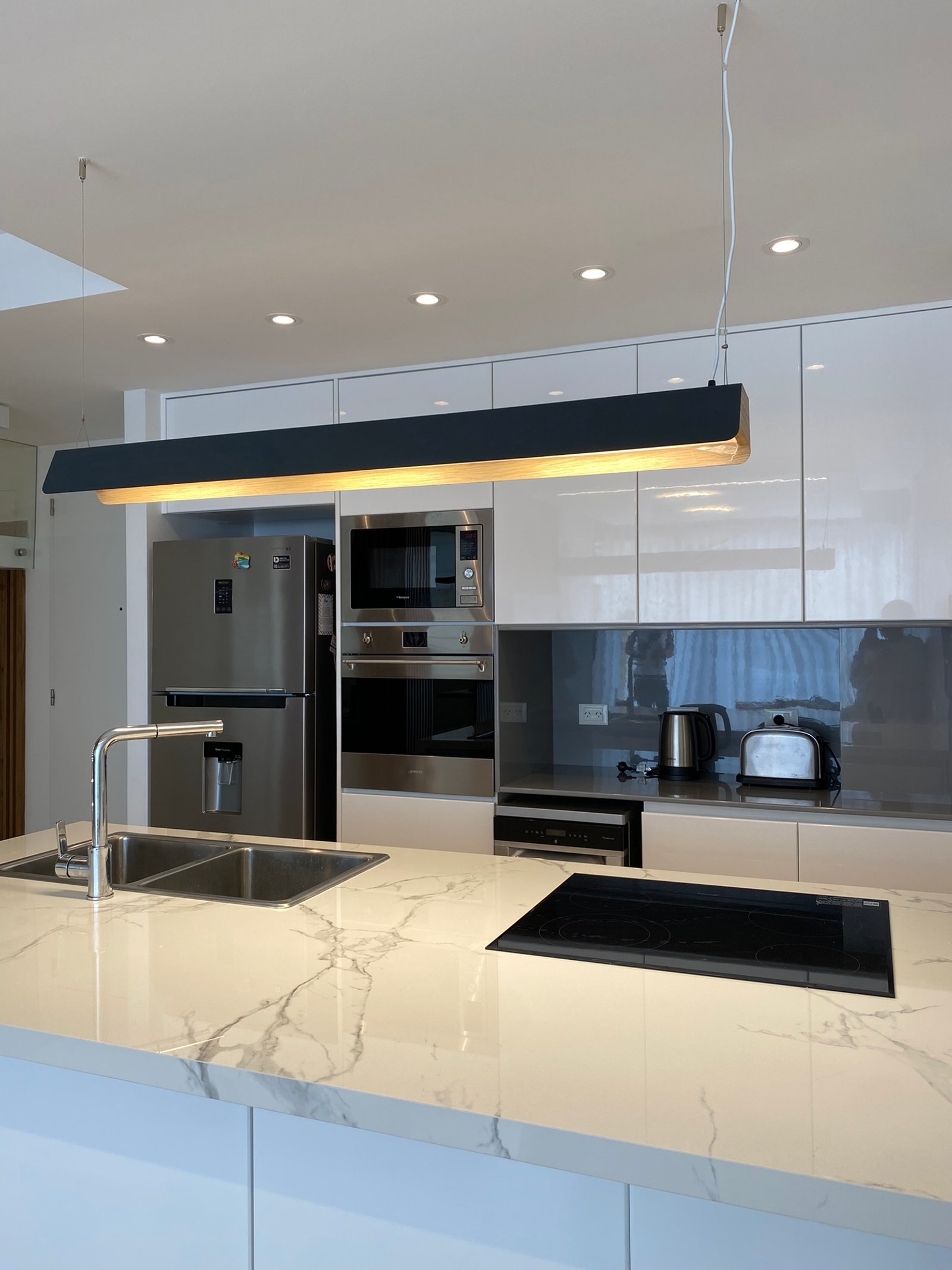Cozinha moderna com ilha de mármore_like, eletrodomésticos integrados — projeto Nicolas Repetto, por MDBK Arquitectura, em Caballito
