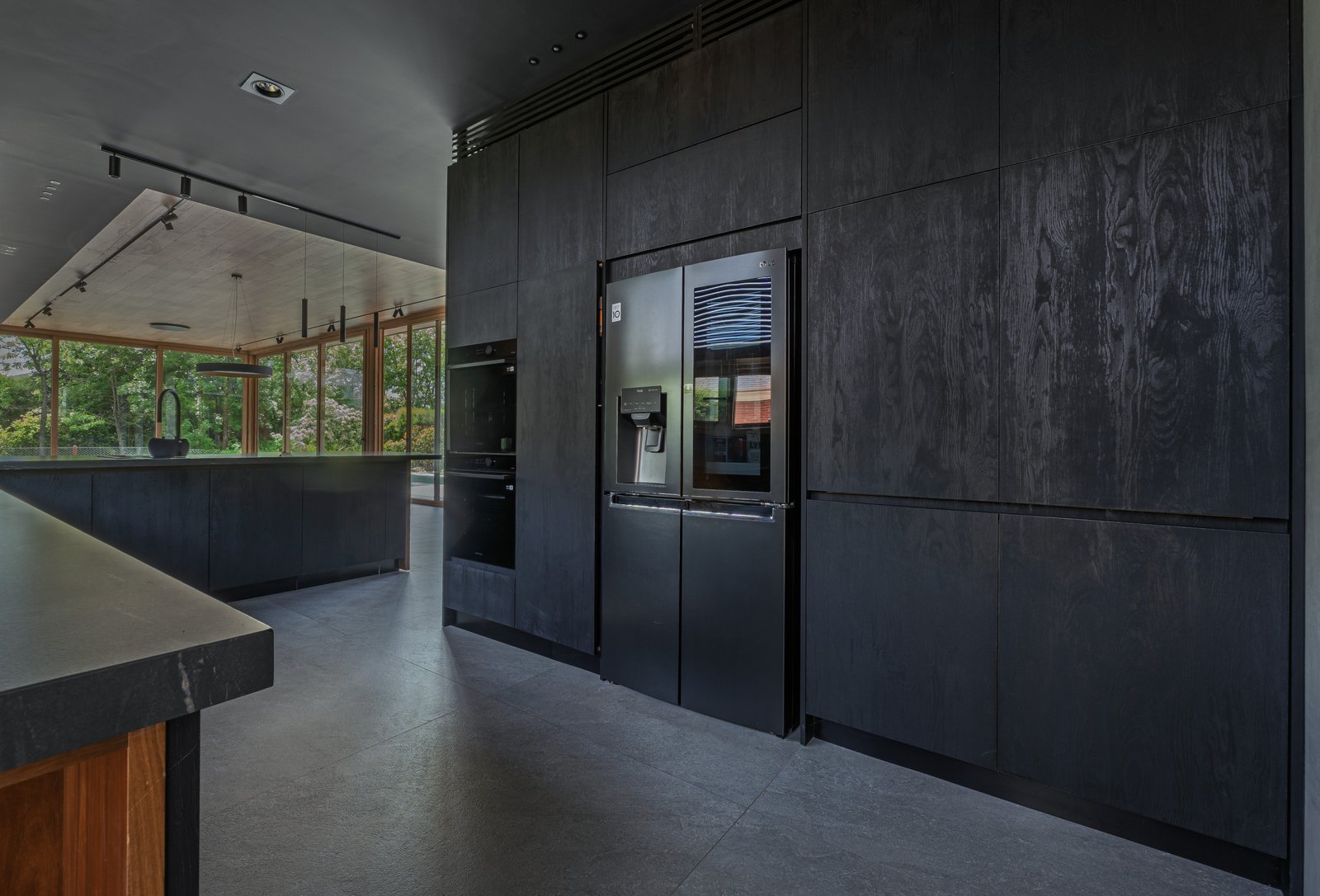 Cozinha moderna em madeira escura com ilha e amplas janelas — projeto Castores - Estudio Gambotto, por ABEJA CONCEPT, em Los Castores