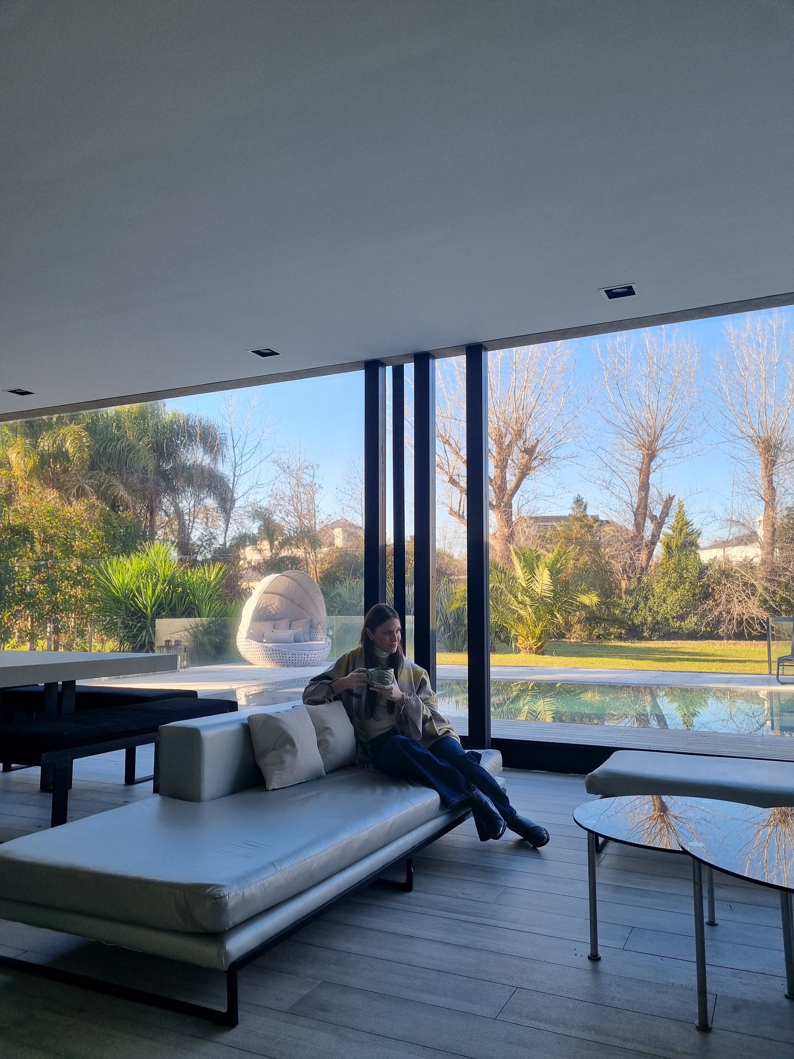 Living moderno con sofá gris y vista a piscina — proyecto Toldos Verticales, por ToldosYa