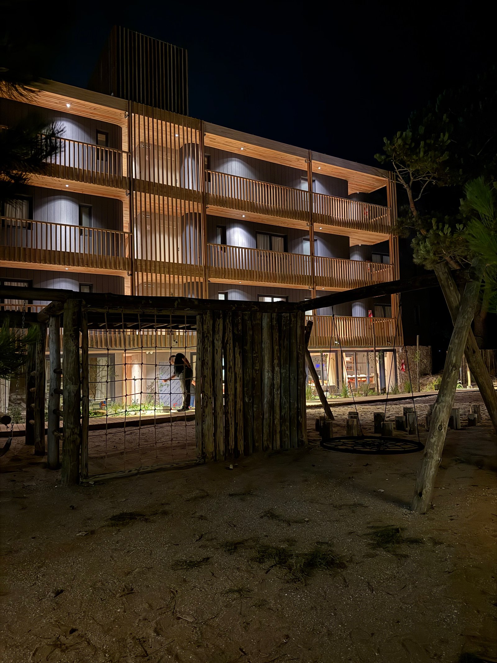 Edifício moderno de madeira com varandas e luzes quentes — projeto Hotel Sustentable, por Marianela Grosso, em Calle 28 & Copacabana