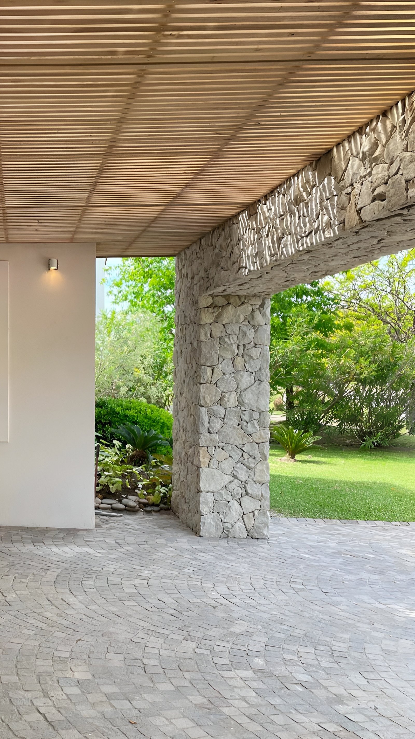Patio moderno con arco de piedra y piso de adoquines curvos — proyecto Casa CC, por Hermann Arquitectos, en Los Castores