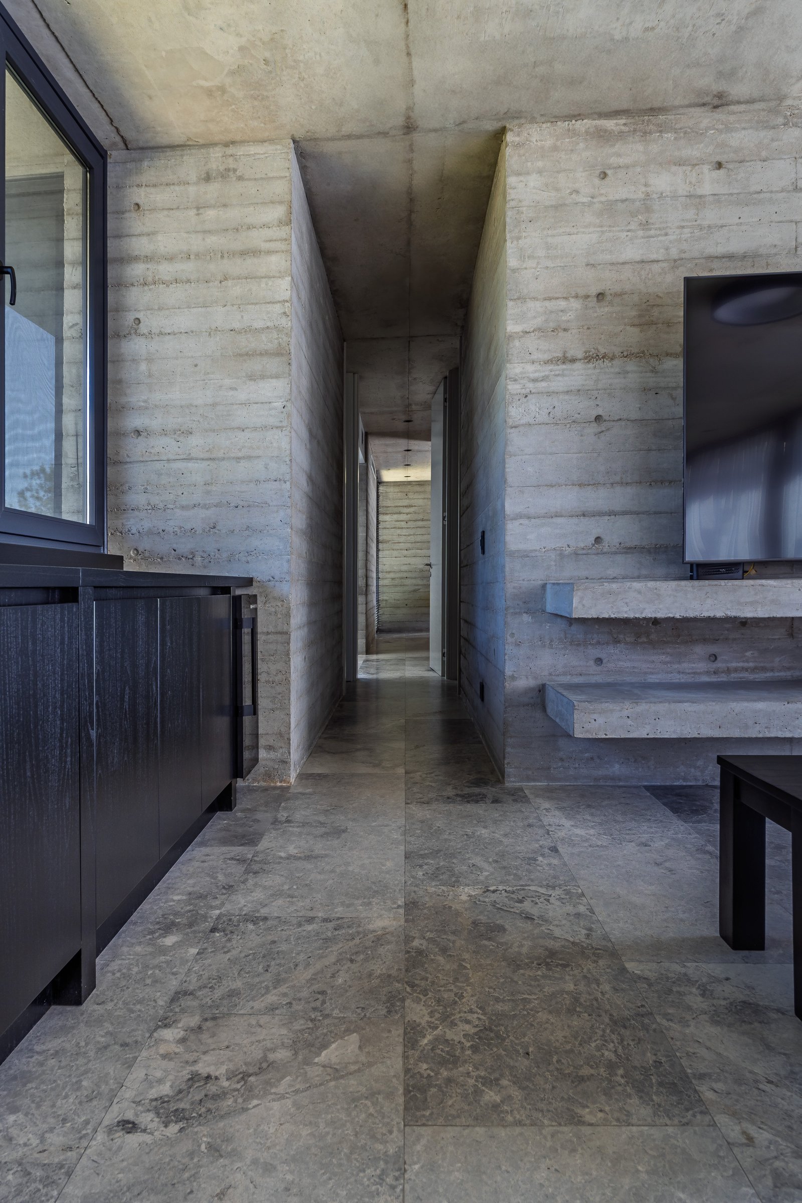 Corredor moderno brutalista com concreto aparente e prateleiras em balanço — projeto La Martona - Estudio Barcelona, por ABEJA CONCEPT, em Cañuelas
