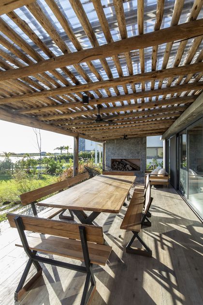 Galería con pergola de madera, mesón y hogar, vista al jardín — proyecto Casa ES, por Facundo Arana Arquitecto