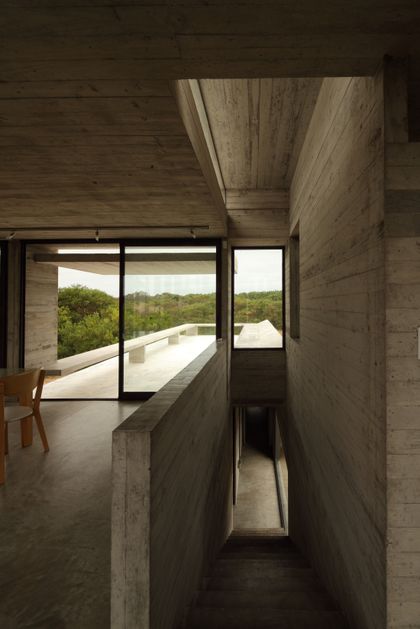 Pasillo de hormigón con vista al paisaje verde y doble altura — proyecto Casa Costa Esmeralda, por Luciano Kruk