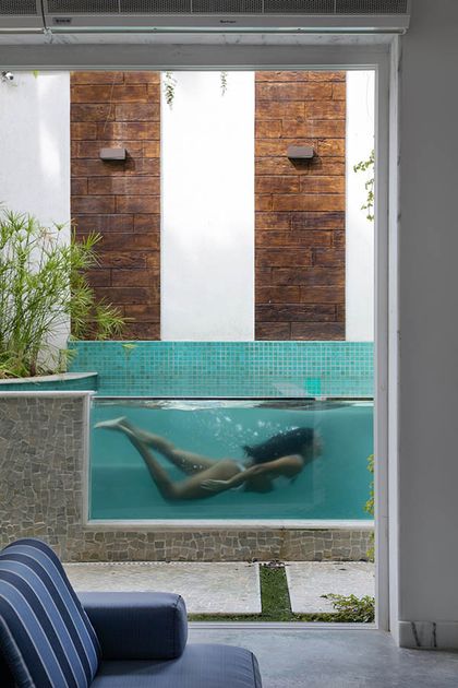 Piscina turquesa moderna con muro ladrillo, vista desde interior — proyecto Casa Jardim Guanabara, por Amanda Miranda