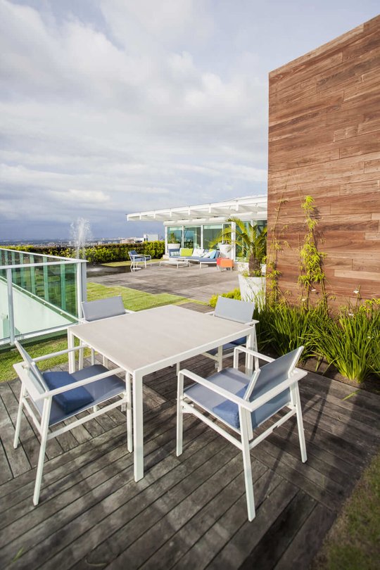 Terraza moderna con mesa blanca, vistas al horizonte y jardín vertical — proyecto Cobertura LS, por Patrícia Marinho Arquitetura 