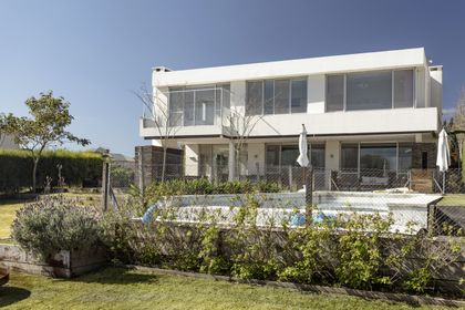 Casa contemporánea con fachada blanca, ventanales amplios y jardín frontal — proyecto Santa Barbara 121, por Build a Home Arquitectura, en B1648 Tigre