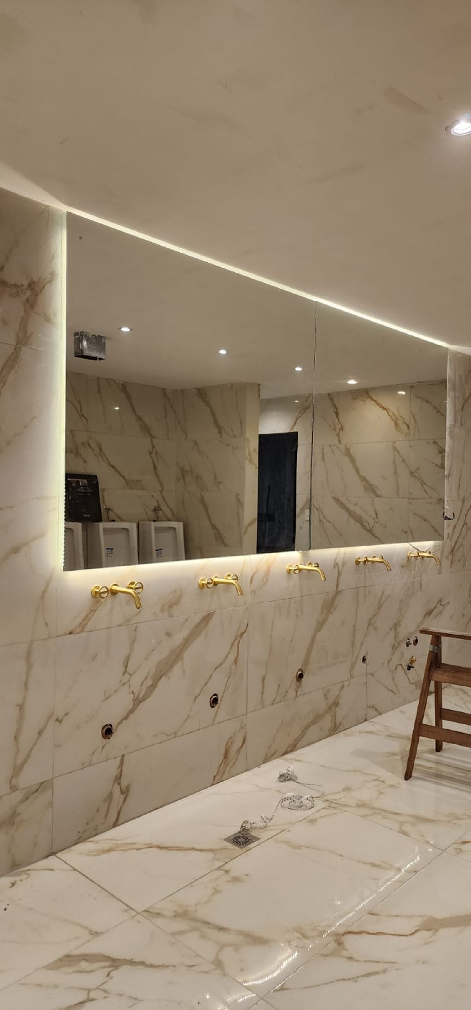 Baño comercial moderno con grifería dorada y paredes de mármol — proyecto BNA CENTRAL ESPEJOS LED, por Cristalcenter, en Centro