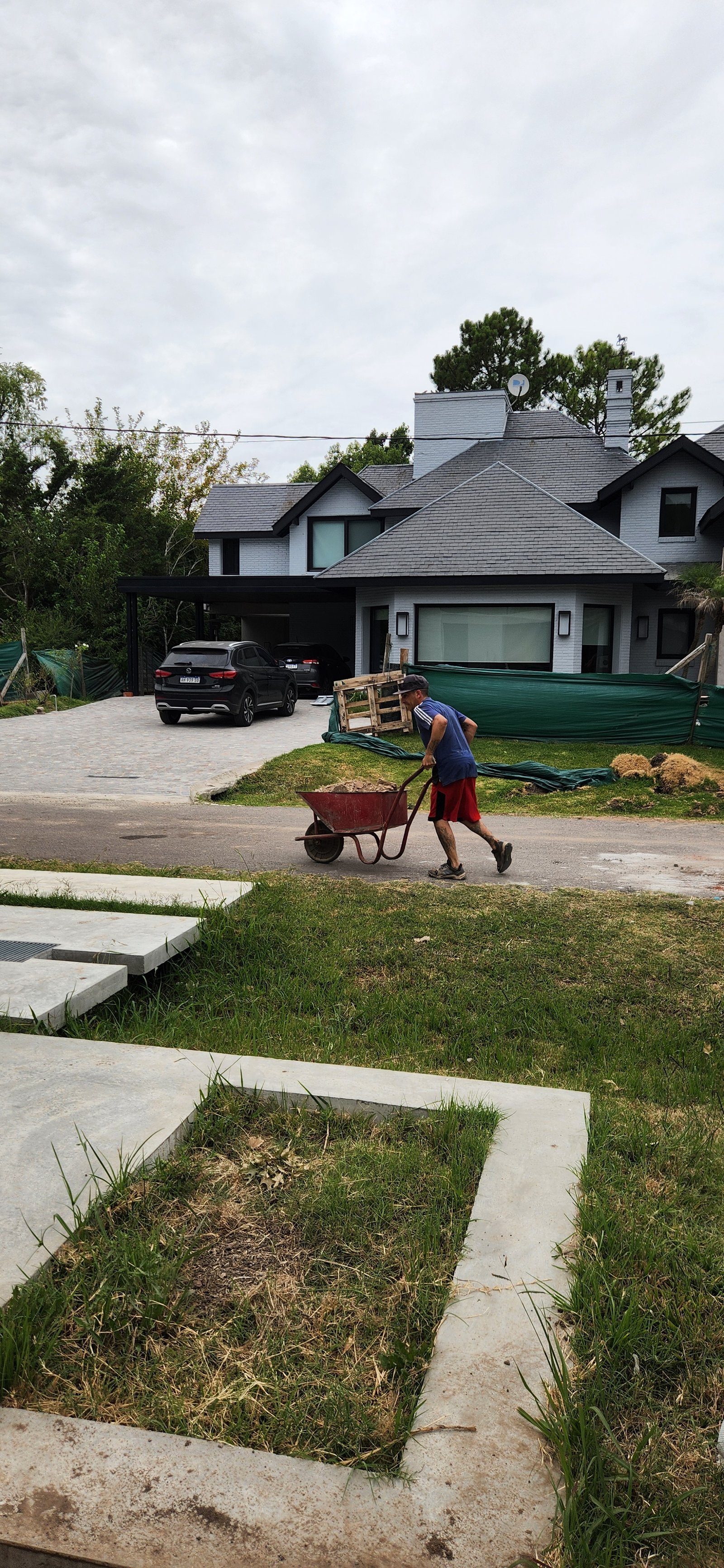 Casa moderna em construção com homem empurrando carrinho de mão — projeto Casa CAD, por Estudio Rifahi, em Moreno