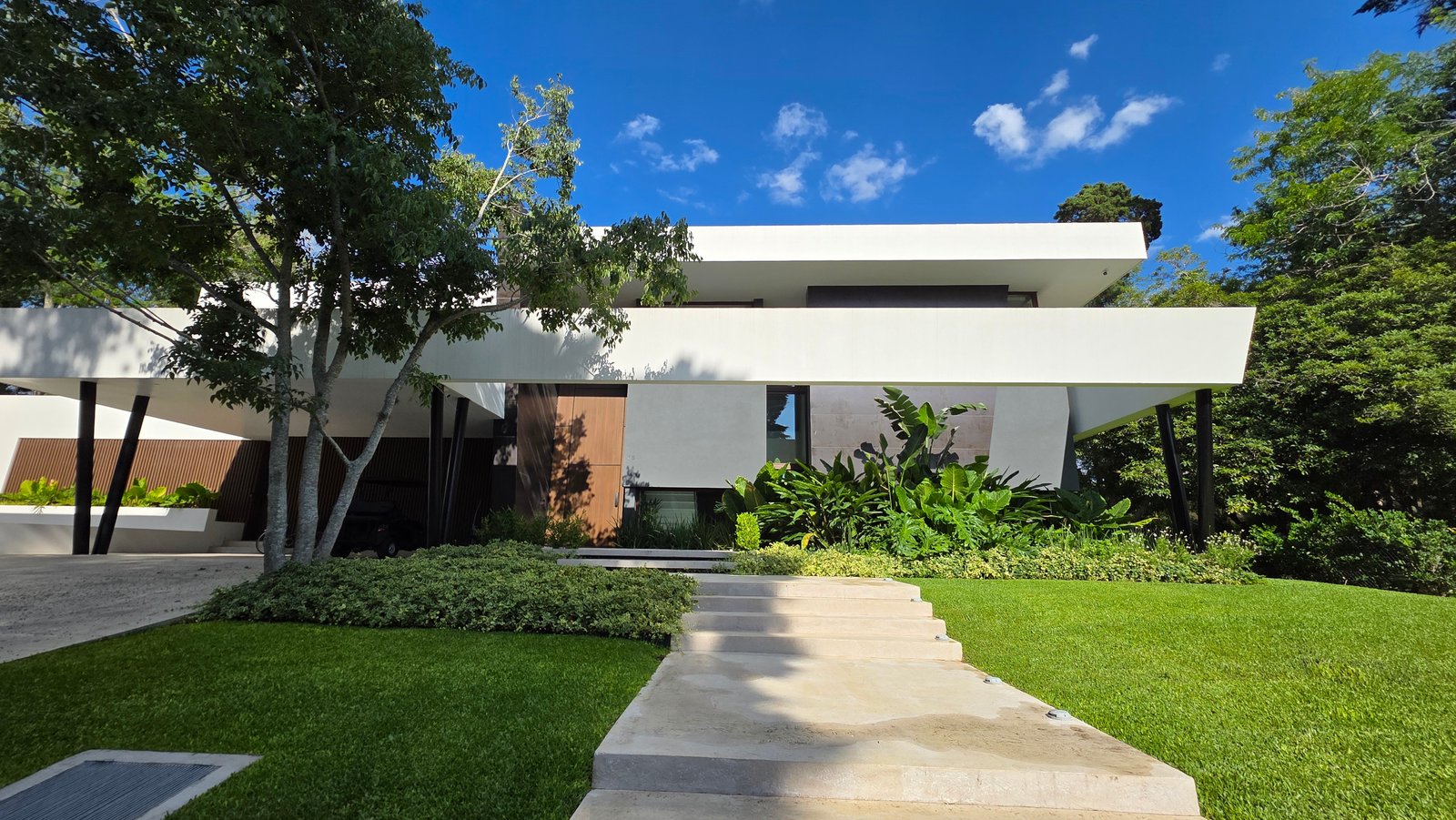 Fachada moderna con jardines integrados y líneas horizontales — proyecto Forest House, por Marcela García Brünner Paisajista, en B1885 Guillermo Enrique Hudson