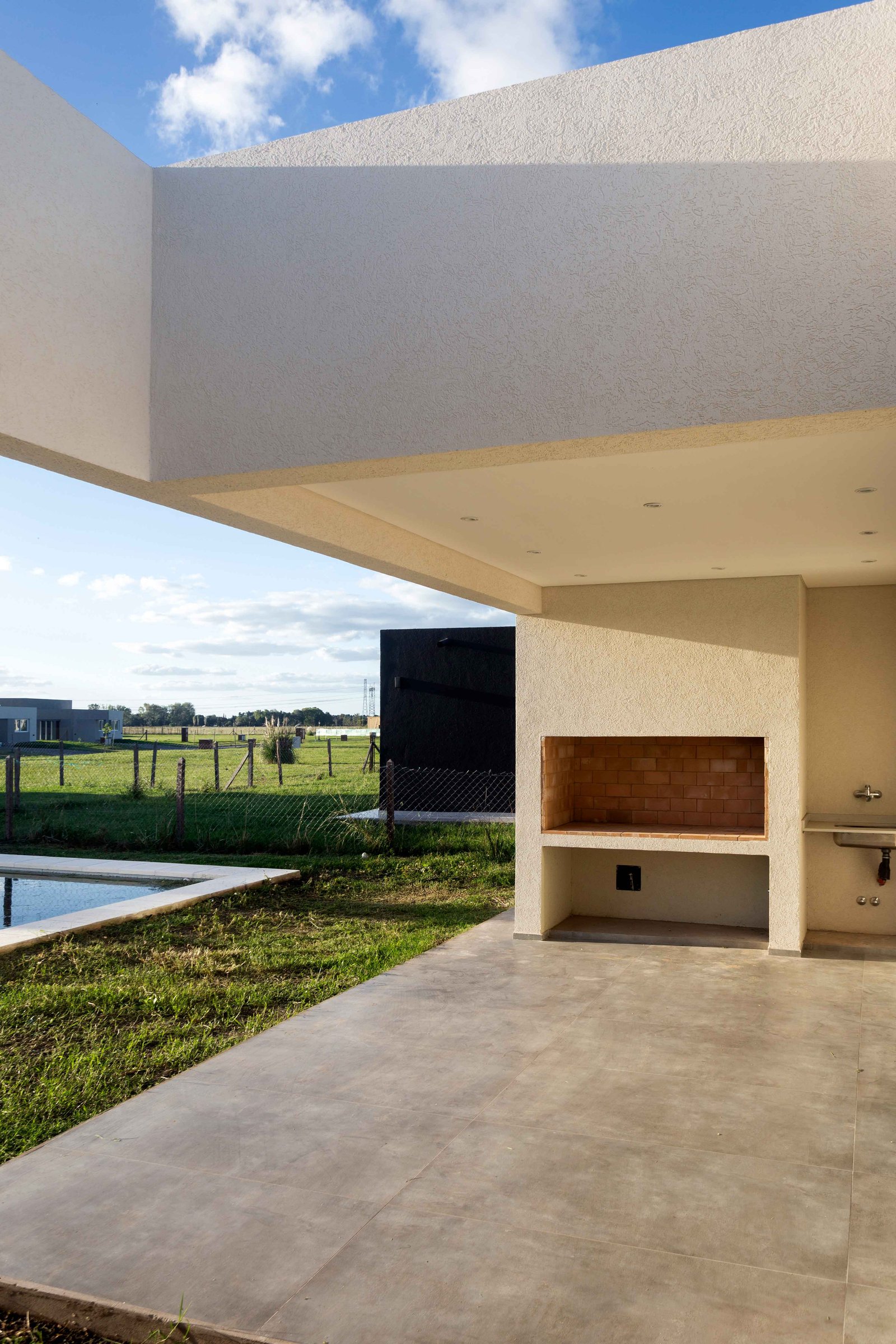 Patio moderno con parrilla y vista al campo — proyecto San Simon I, por Estudio Stepa, en Ezeiza