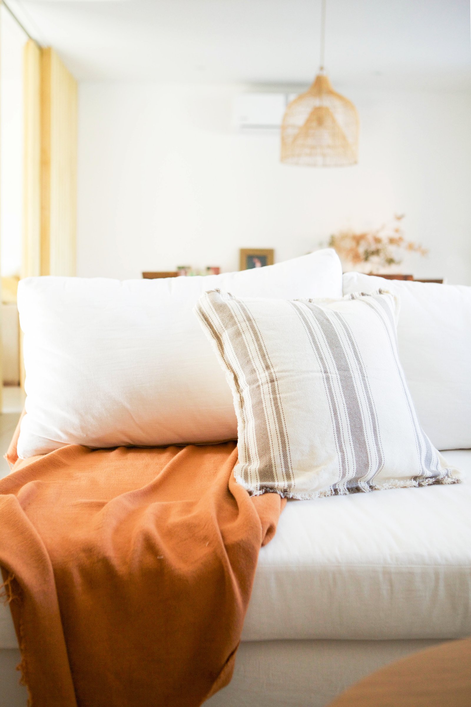 Sofá modular blanco, manta naranja y lámpara de mimbre — proyecto Javo, por LACROZE DESIGN STUDIO, en San Isidro