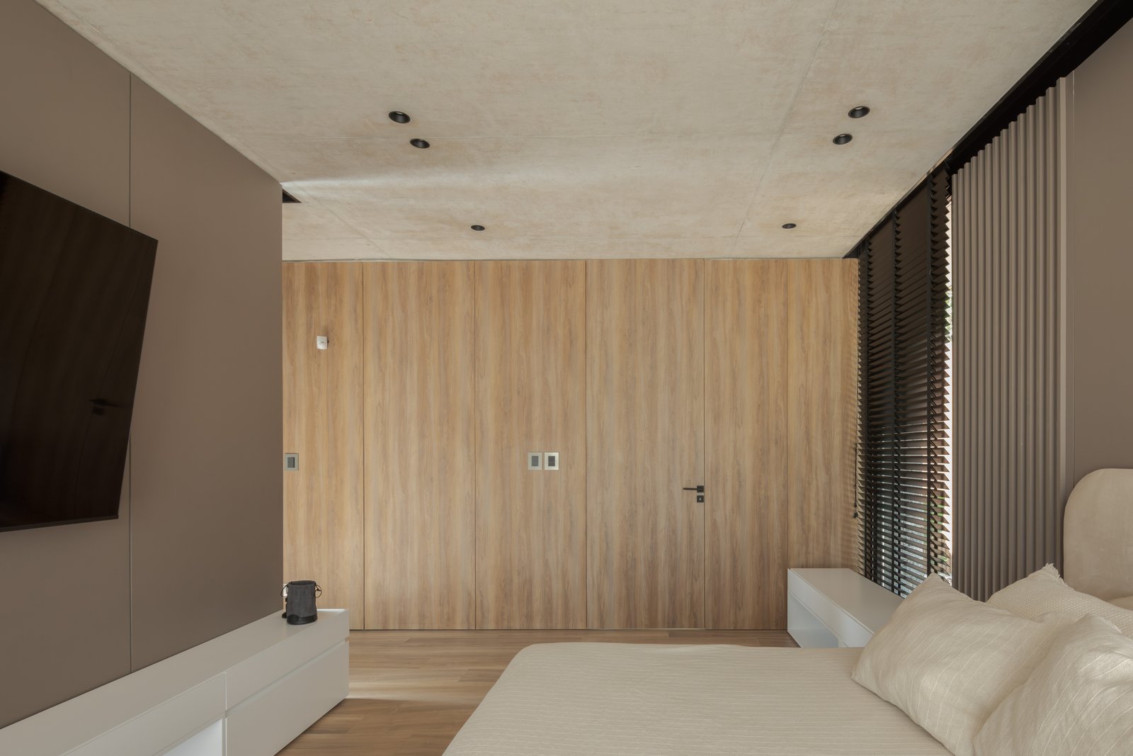 Dormitorio moderno minimalista con paredes de madera y TV empotrada — proyecto Casa PLANALTO, por Grupo CRBN, en Av. Pres. Perón 10298