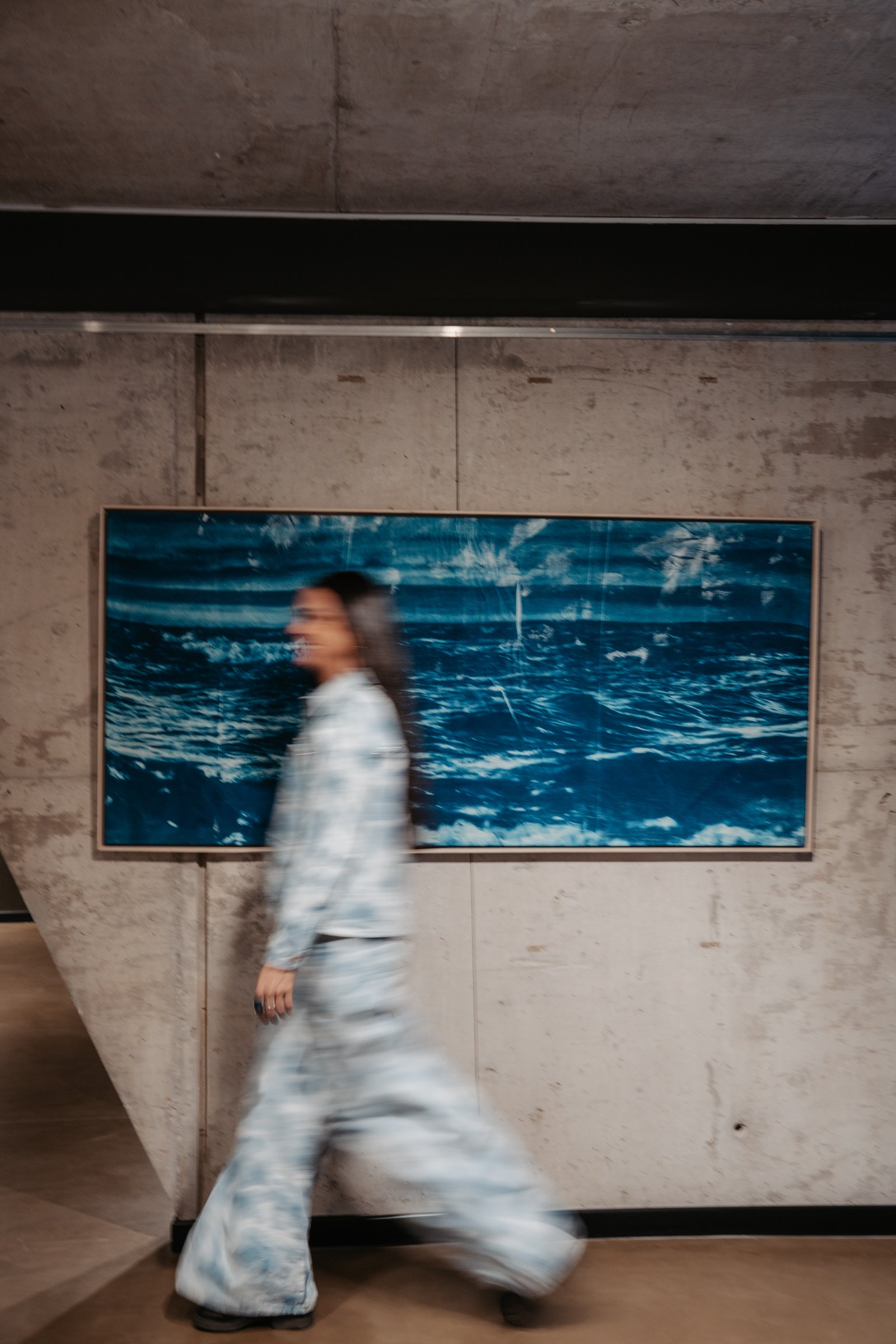 Pasillo industrial con obra de arte abstracta y figura borrosa — proyecto The Blue Exhibition, por AGUSTINA RUIZ ARTE, en Puerto Madero