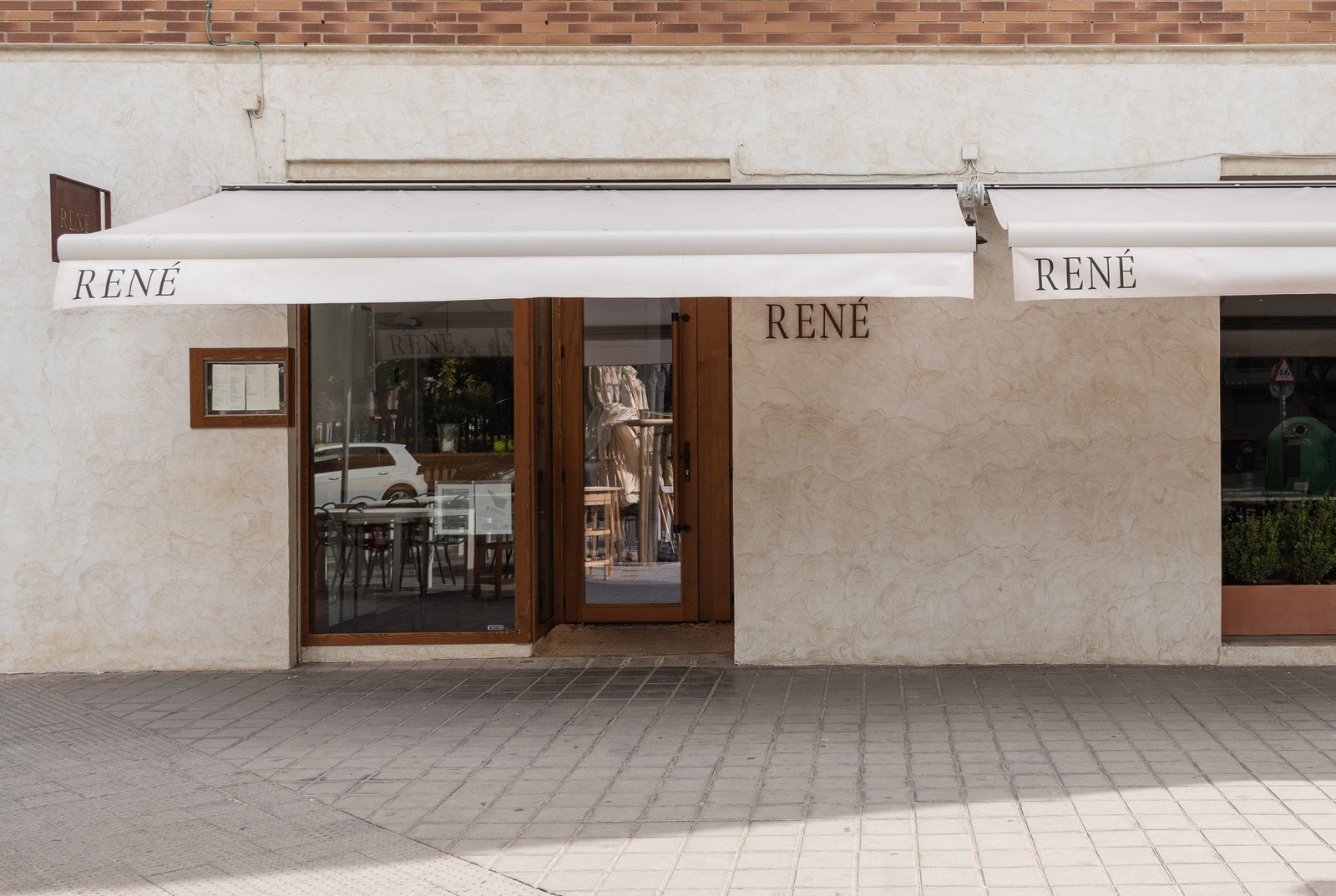 Fachada de restaurante moderno con toldo y detalles en microcemento — proyecto René Restaurant, por JT ARQUITECTURA, en Valencia
