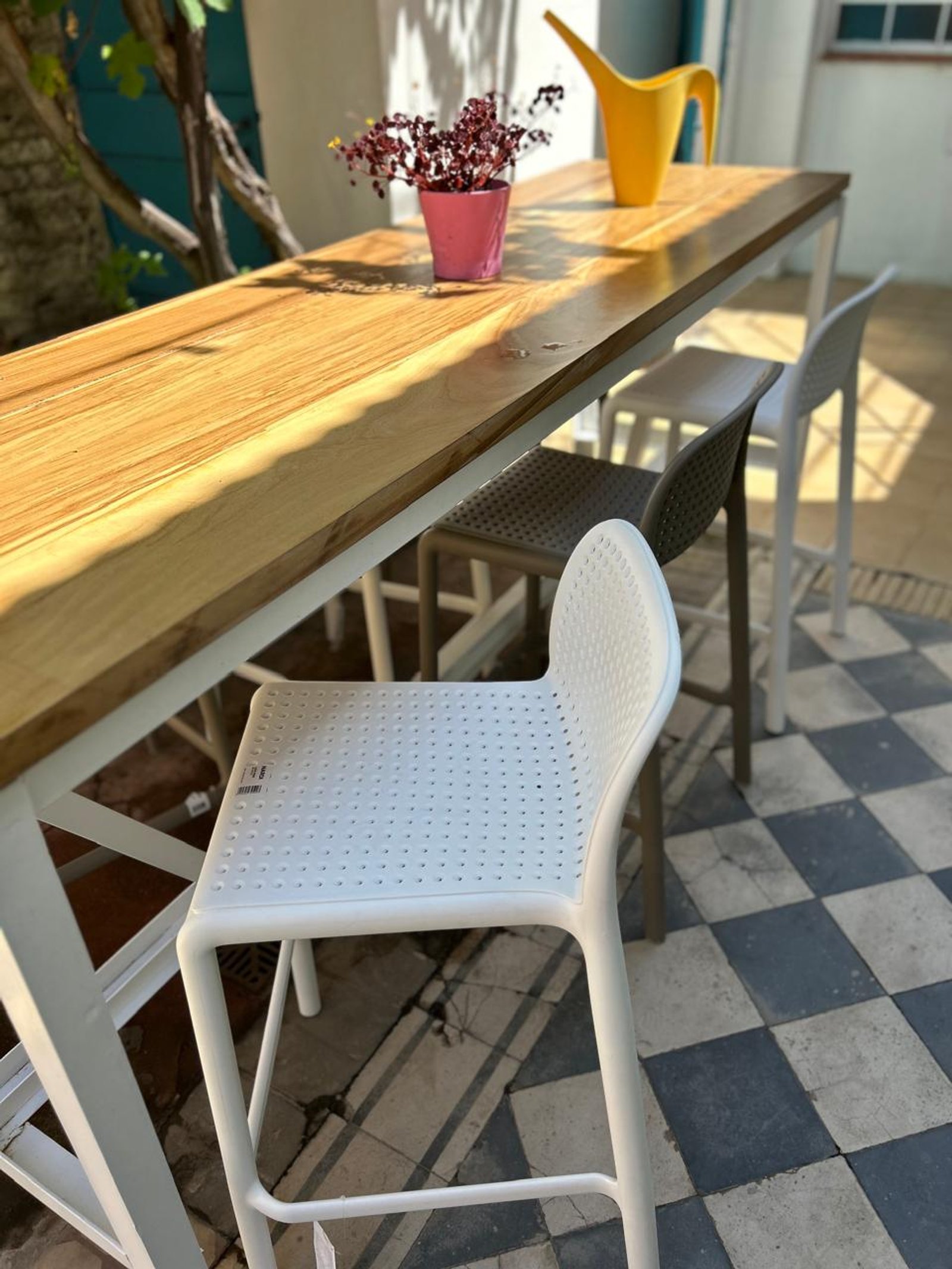 Mesa alta de madera y banquetas de plástico en patio exterior — proyecto Barras, por Casa Nuñez