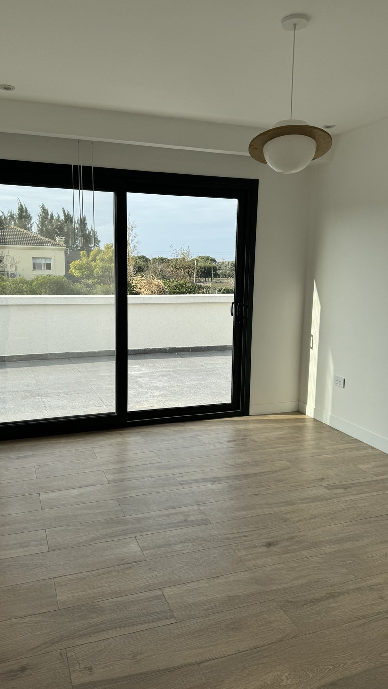 Terraza moderna con piso símil madera y puerta de vidrio corrediza — proyecto Casa MC, por Hermann Arquitectos, en Bv. Central