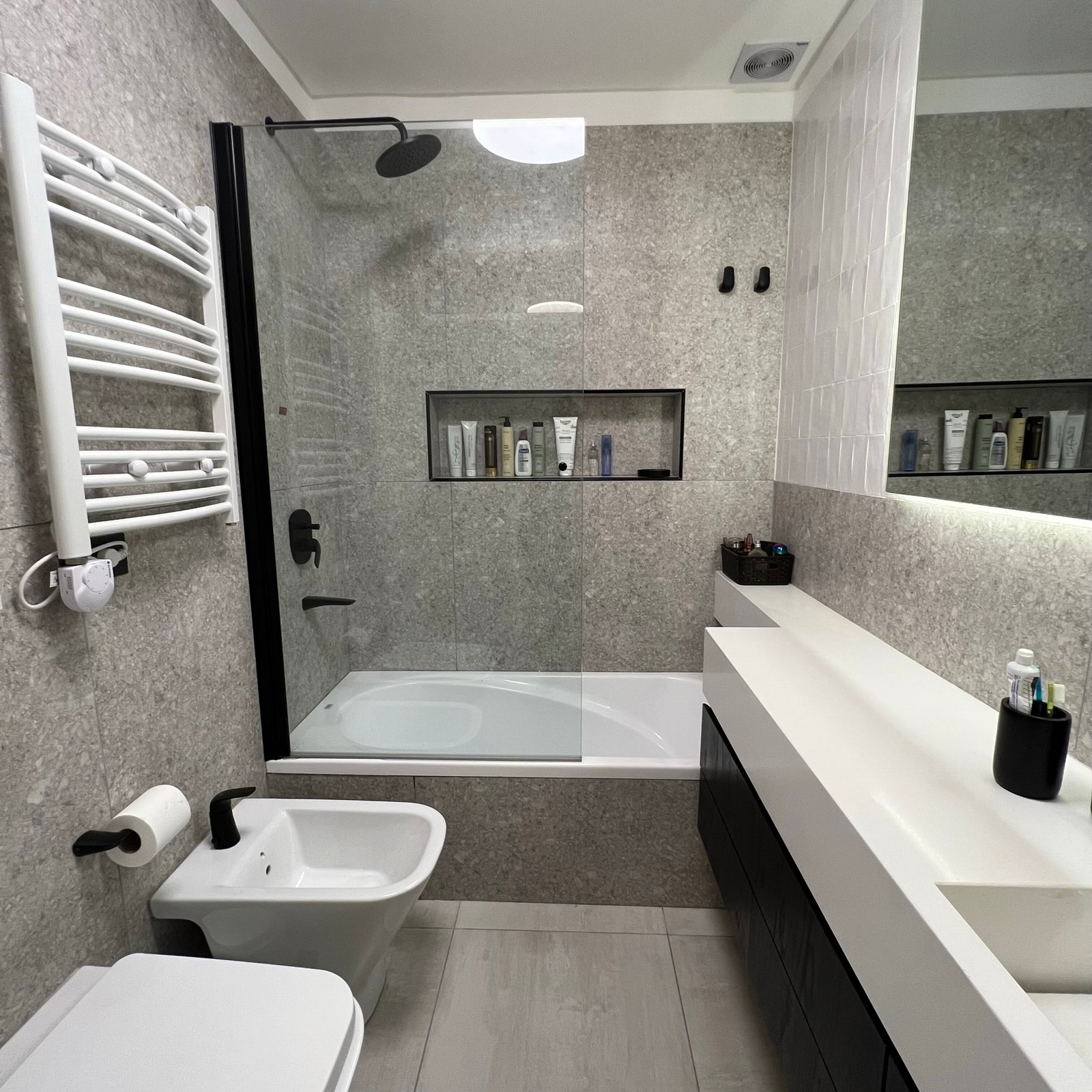 Baño moderno con paredes texturizadas, bañera y ducha integradas — proyecto Cranwell, por MDBK Arquitectura, en Flores