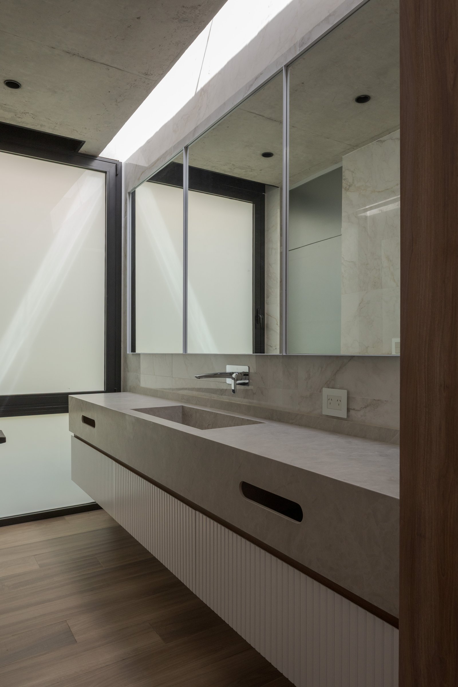Baño moderno con bacha de cemento, revestimientos de mármol y claraboya — proyecto Casa PLANALTO, por Grupo CRBN, en Av. Pres. Perón 10298