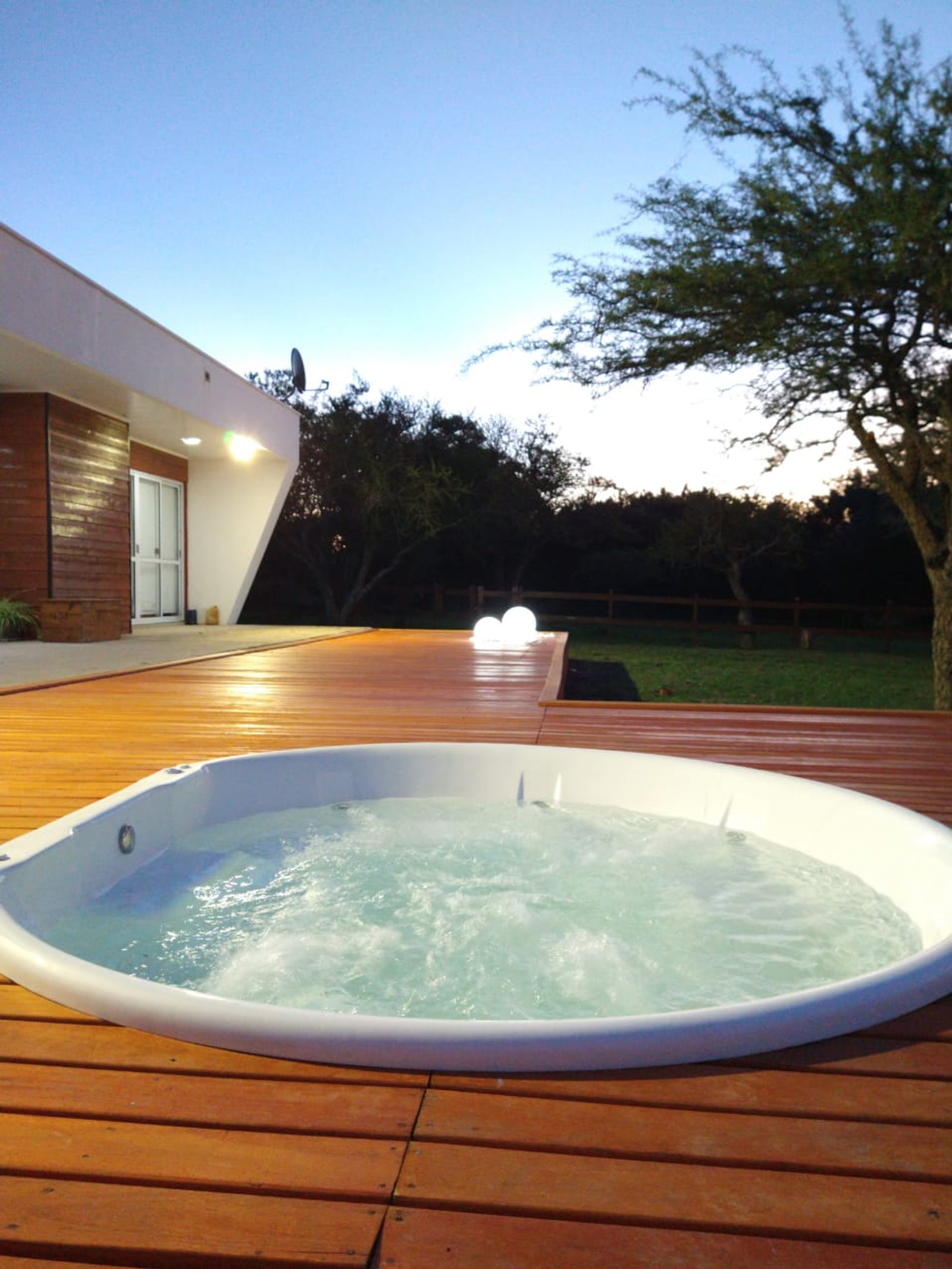 Jacuzzi exterior en deck de madera con fachada moderna — proyecto Jacuzzi en Deck, por Kardiona, en Villa Elisa