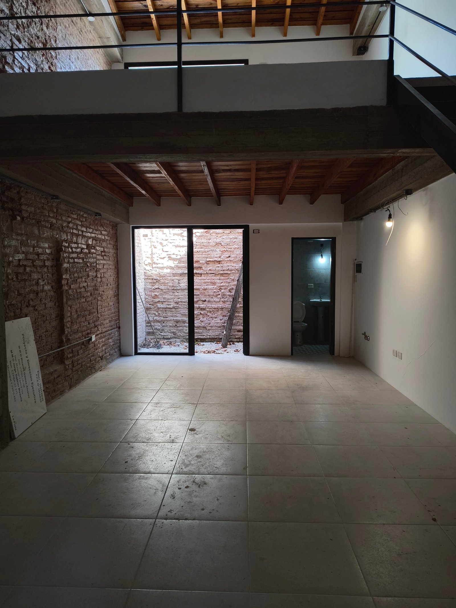 Espacio industrial de doble altura con entrepiso y escalera flotante — proyecto La tienda del jugador | Diseño de local comercial, por Ludmila Ortega diseño, en C. 15 & C. 57