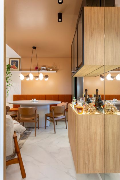 Comedor contemporaneo con banqueta naranja, mesada marmol y doble altura — proyecto #ApêCoolColors, por Oficina de Morar, en Jaraguá do Sul - Barra do Rio do Cerro