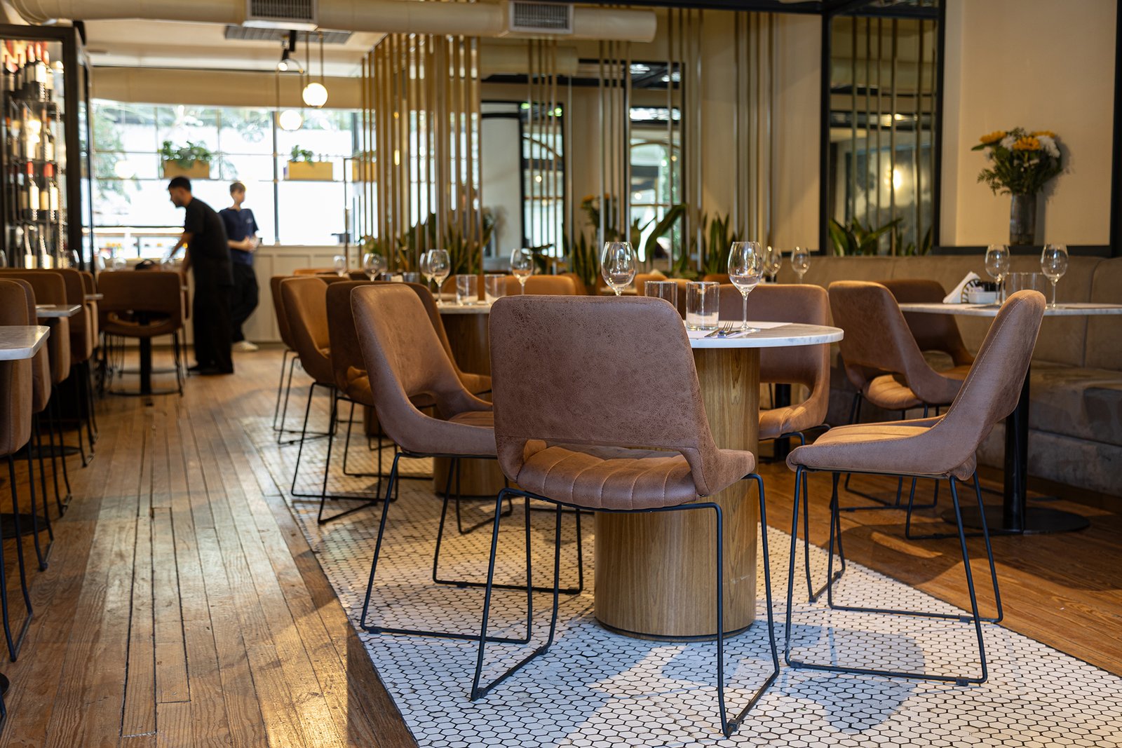Sala de jantar de restaurante com mesas de madeira e cadeiras estofadas — projeto Olivier BA, por Gaby Alfonso, em Belgrano