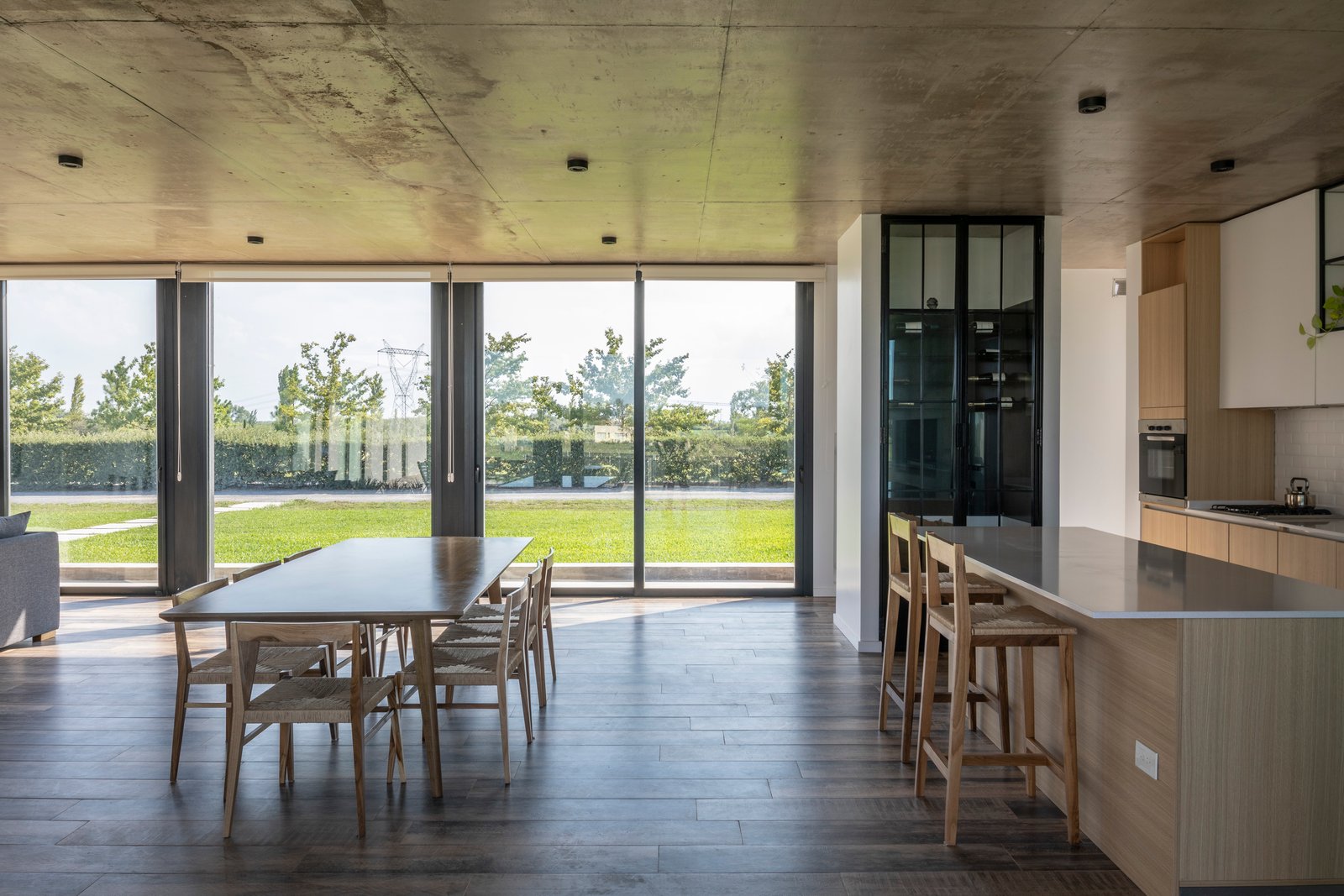 Sala de jantar moderna integrada à cozinha com teto de concreto aparente — projeto Casa Cruz, por Grupo CRBN, em B2812 Exaltación de la Cruz