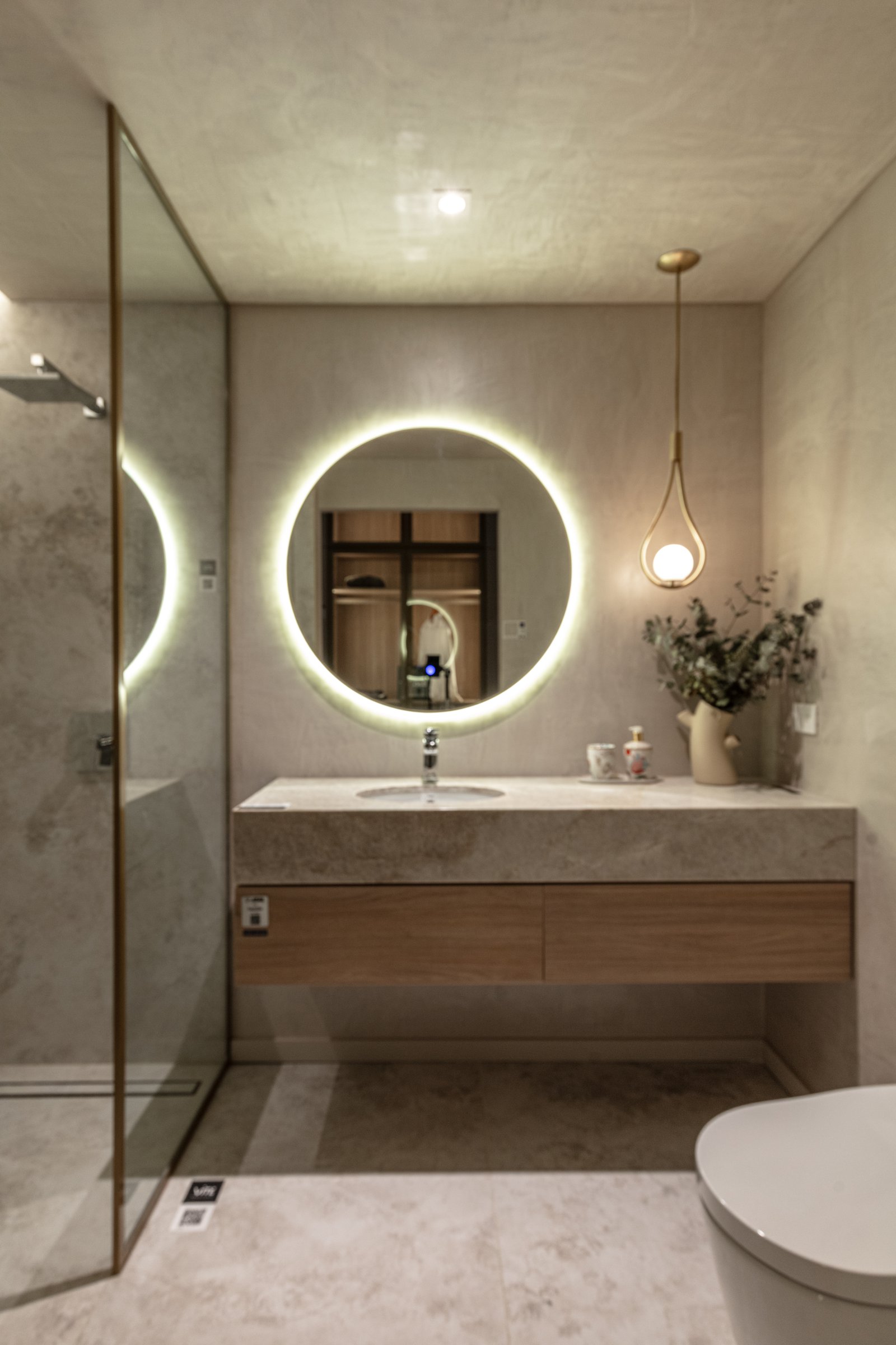 Baño moderno con espejo redondo retroiluminado y vanitory de madera — proyecto Casa Foa Madero Harbour, por Vite Porcellanato, en Buenos Aires