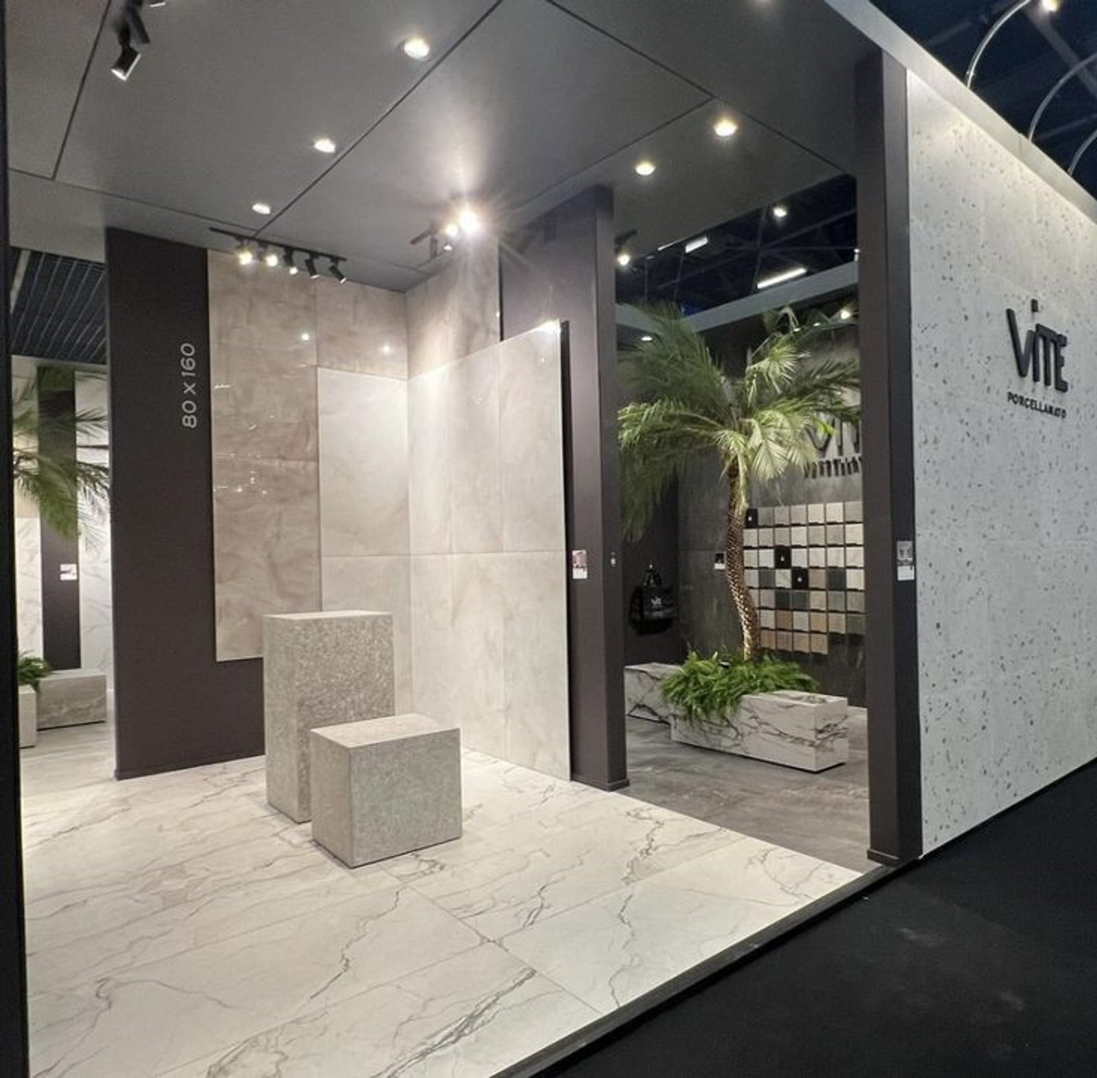 sala de exposición moderna con revestimientos de mármol y exhibidores geométricos — proyecto Expo Revestir 2024, por Vite Porcellanato, en São Paulo