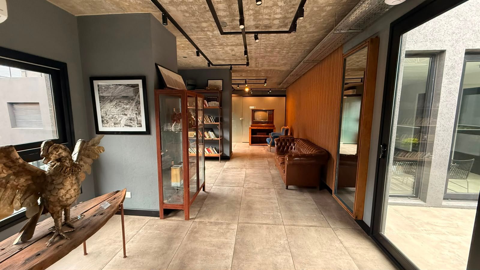 Pasillo de local comercial con vitrinas industriales y detalles en madera — proyecto UNDICI - Howard Johnson- La Boca, por COMOTTO - SOMMER  - ARQUITECTOS, en Brandsen 927