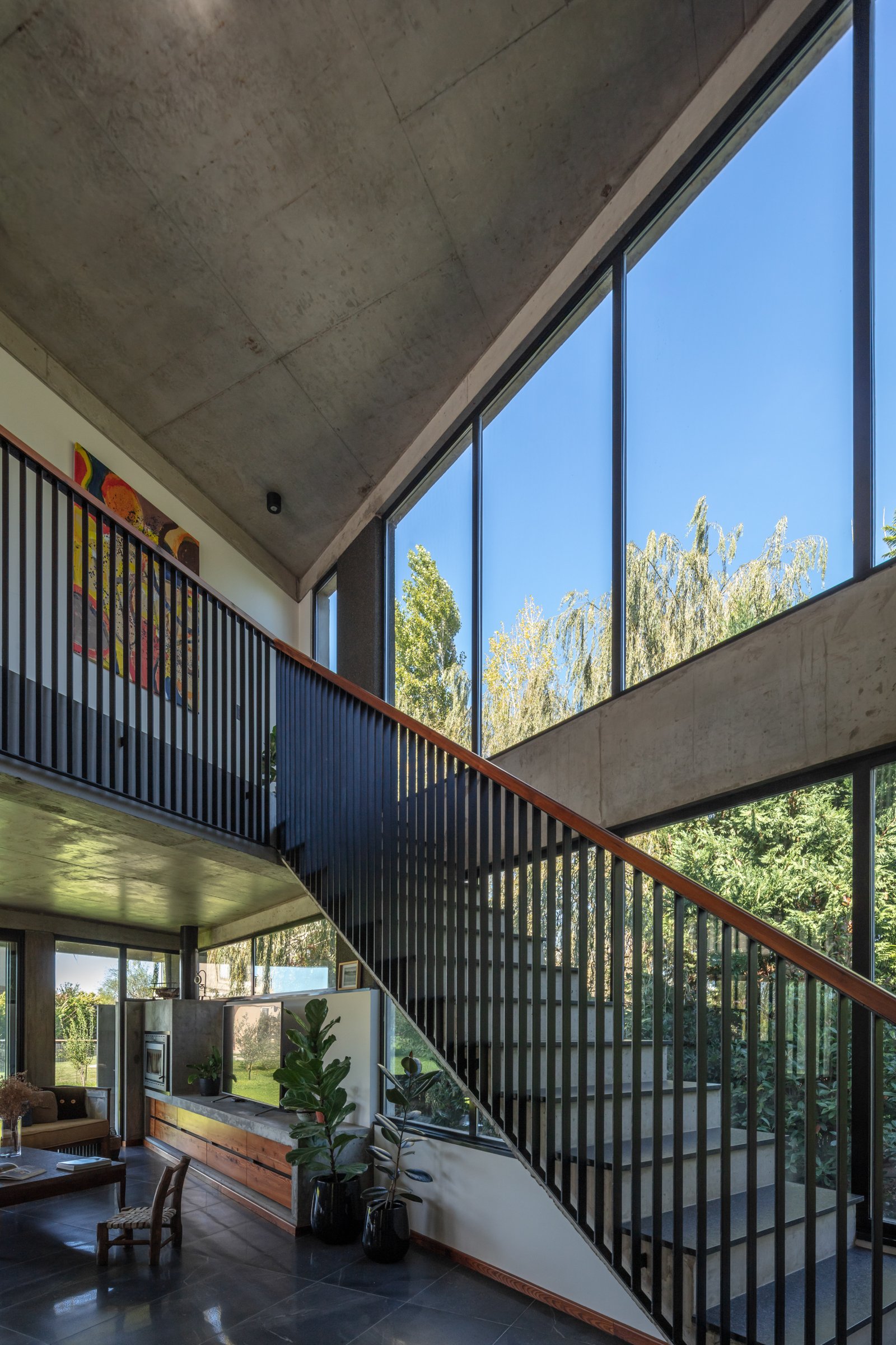 Interior moderno con escalera flotante y ventanales al bosque — proyecto La Martona UF280, por BARBALACO ARQUITECTOS, en Provincia de Buenos Aires