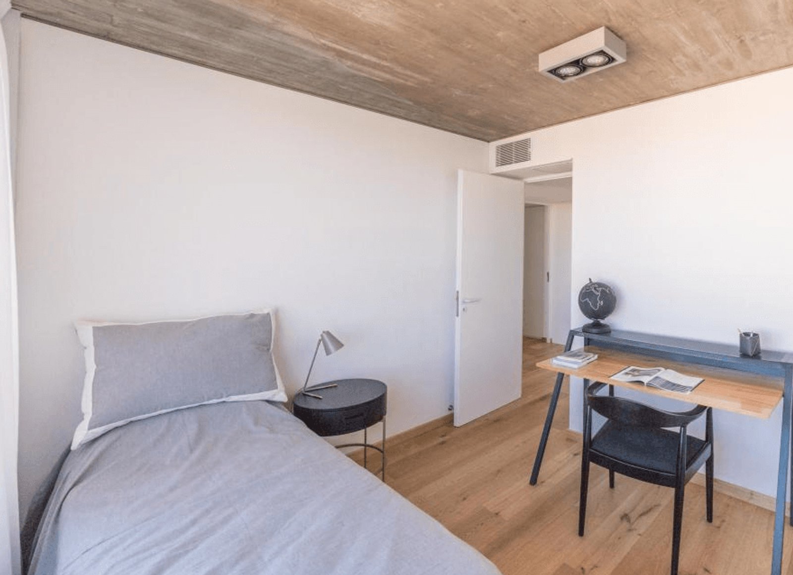 Dormitorio moderno con techo de hormigón y escritorio — proyecto Costavia, por Quento, en Av. Rivadavia 2569