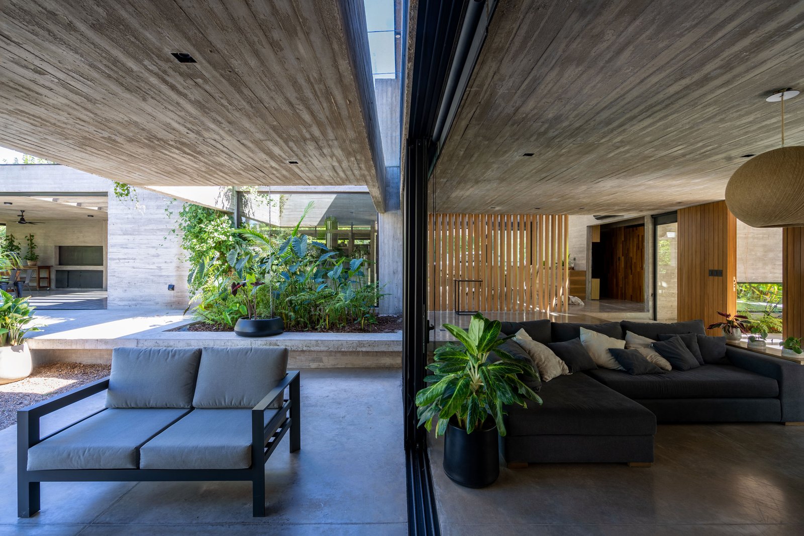 Living moderno con hormigón expuesto y conexión exterior — proyecto Casa Leloir, por Besonías Almeida arquitectos, en Parque Leloir